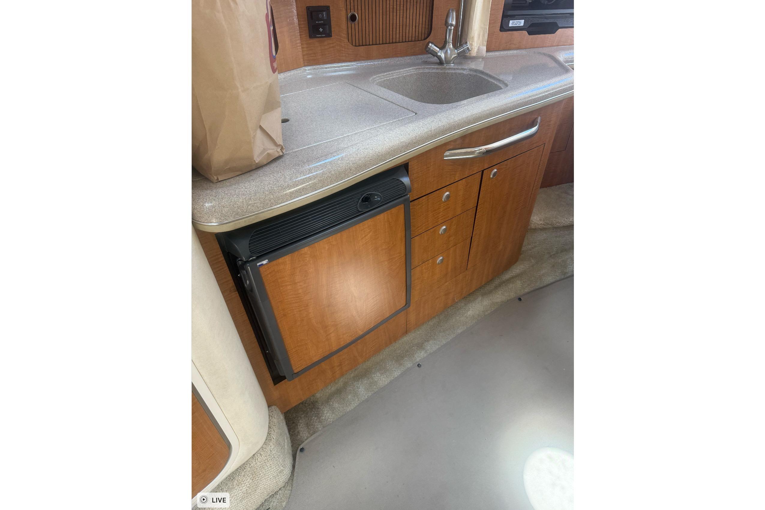 2006 Sea Ray 300 Sundancer interior kitchen with sink and mini fridge.