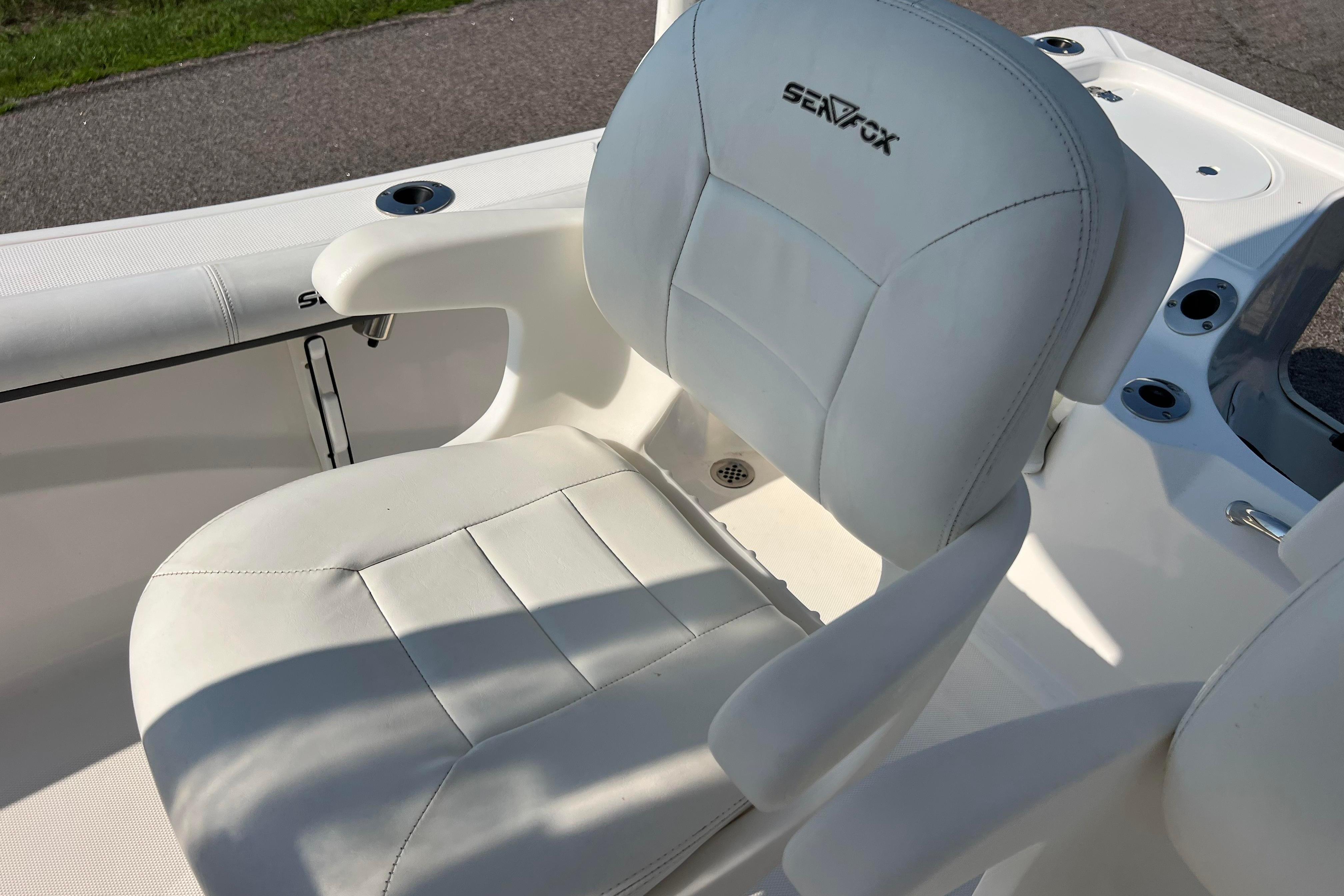 White leather seat on 2012 Sea Fox 206 Center Console boat, featuring armrests and cup holders.