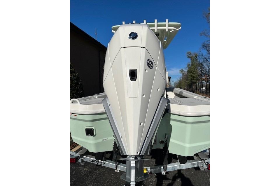 2026 Mako 24 APEX boat on trailer, viewed from the rear under clear blue sky.
