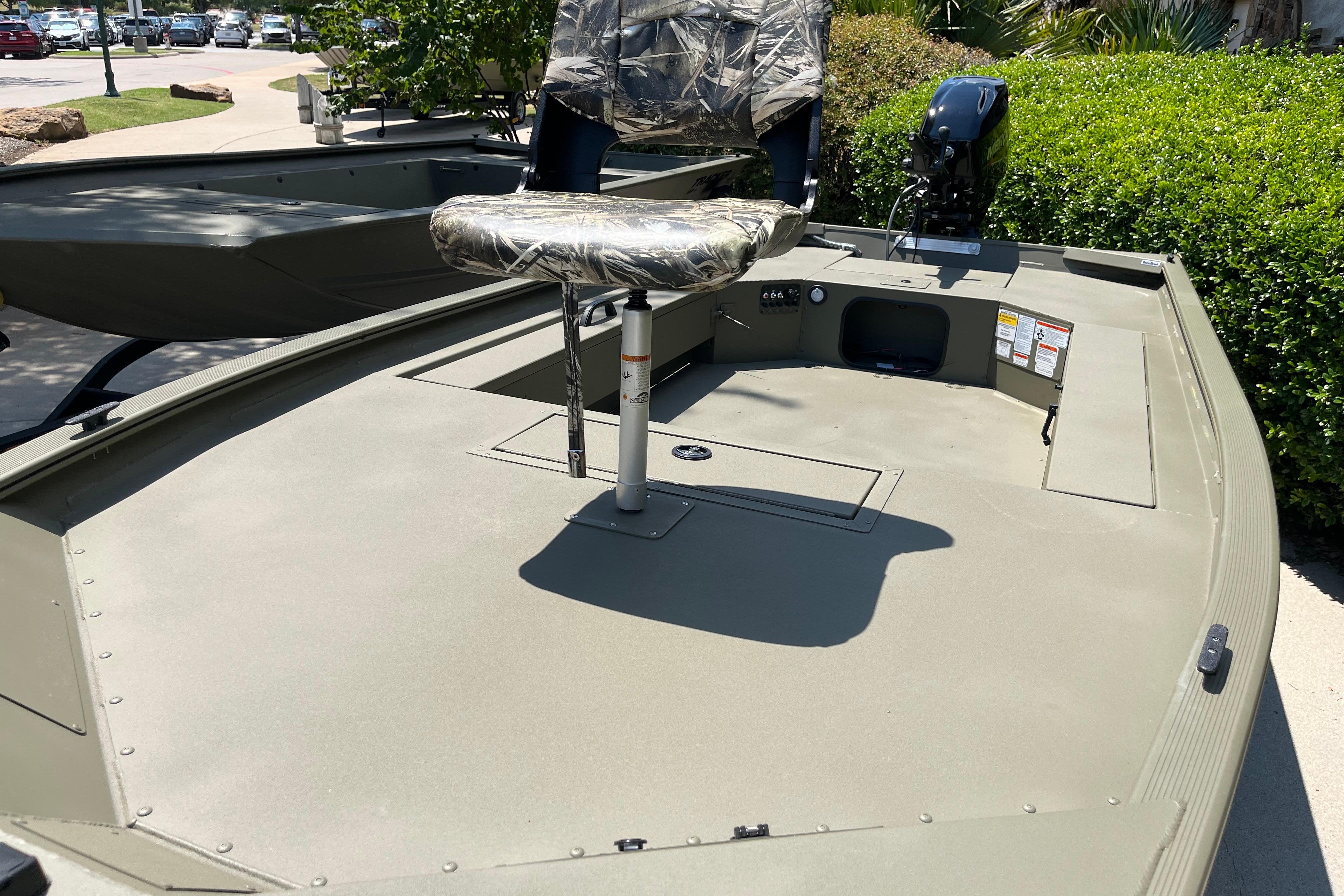 2026 Tracker Grizzly 1654 T Sportsman boat with camo seat and motor, parked outdoors.