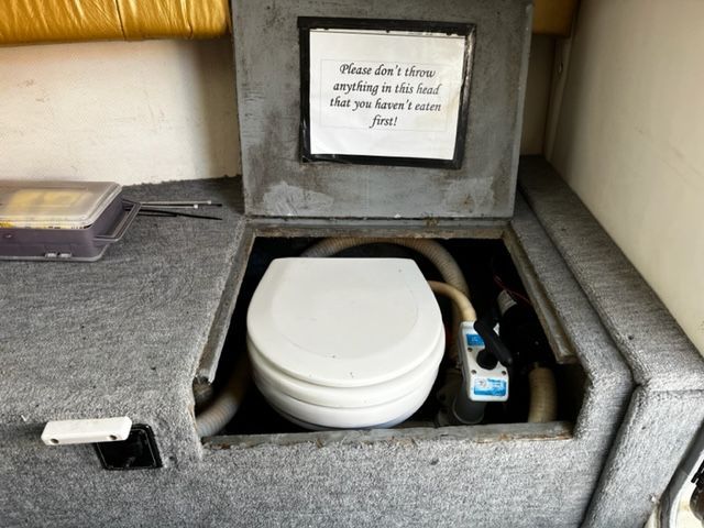A boat toilet with a humorous sign asking for careful flushing.