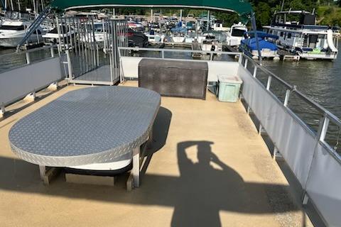 Upper deck of 1995 Myacht 40X13 houseboat with table, seating, and marina view.