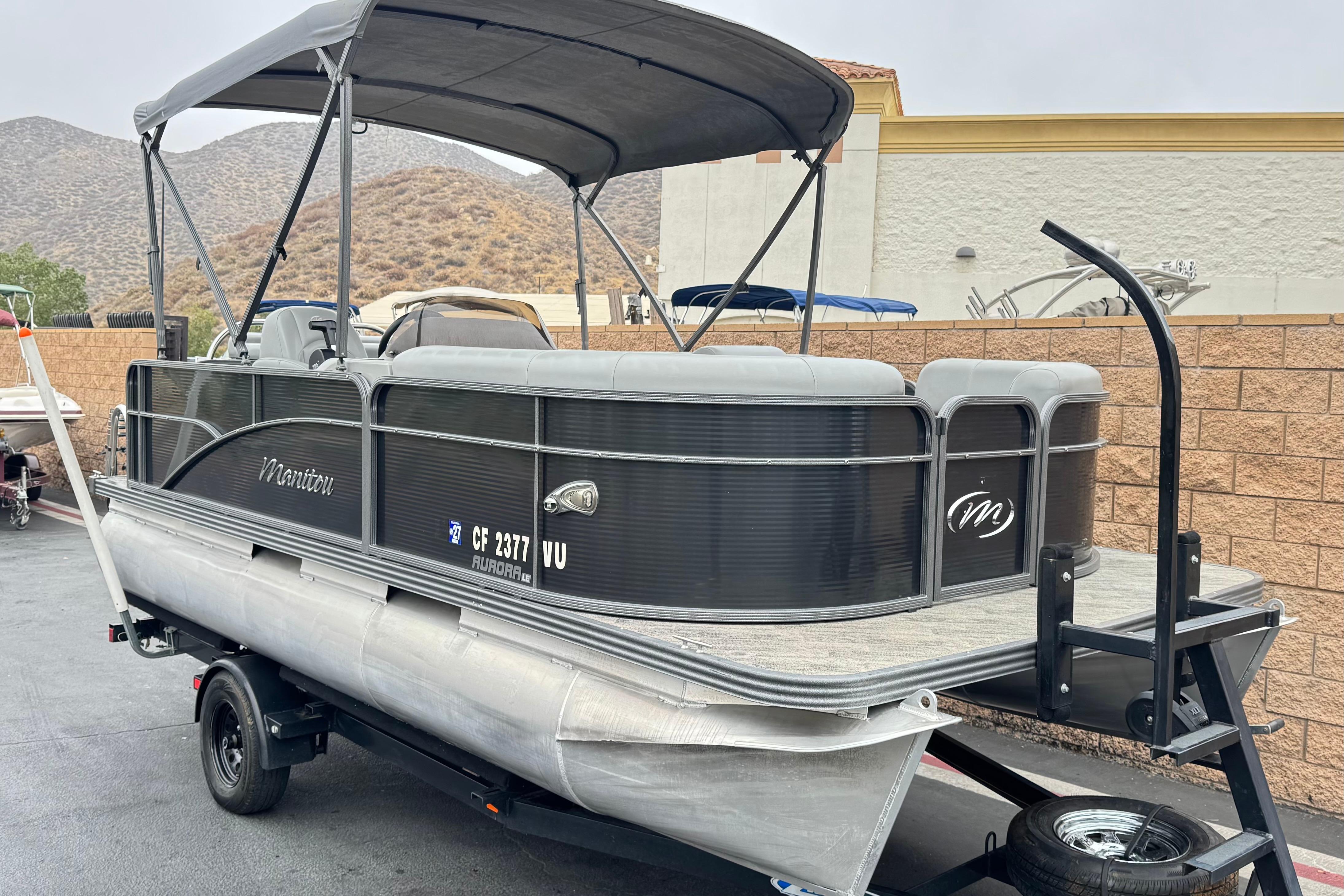 2020 Manitou 18 Aurora LE pontoon boat on trailer, parked outdoors.
