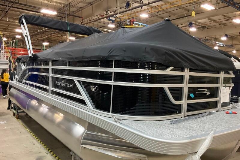 2026 Bennington 22 SSRSF pontoon boat with black cover in a factory setting.