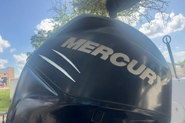 Mercury outboard motor on 1999 Hurricane SunDeck Sport 201 OB boat under blue sky.