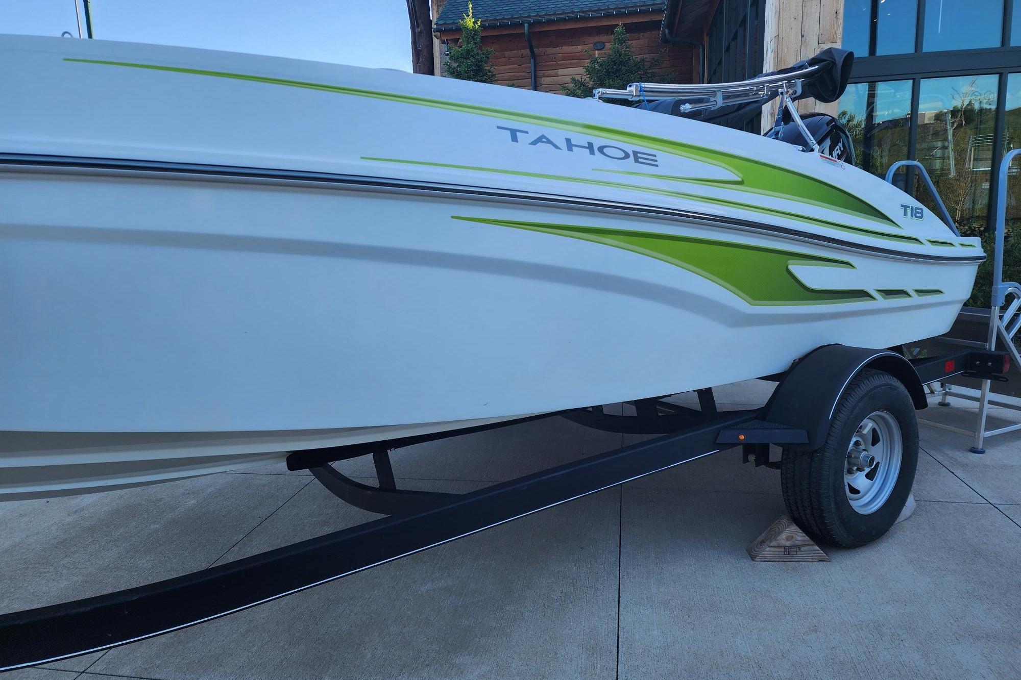2023 Tahoe T18 boat with green accents on a trailer, parked outdoors.