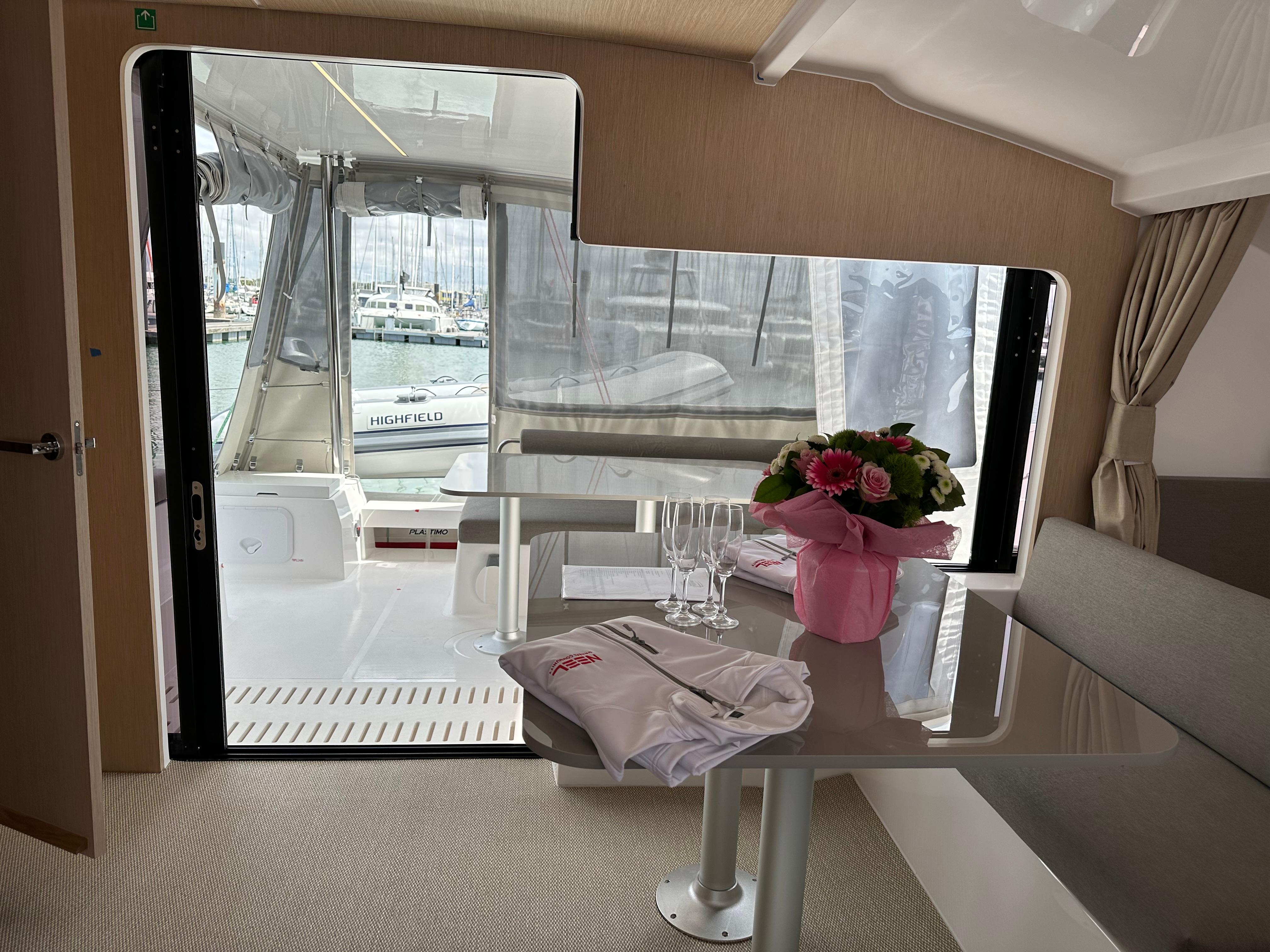 Interior of 2023 NEEL 43 yacht with table, flowers, and marina view.