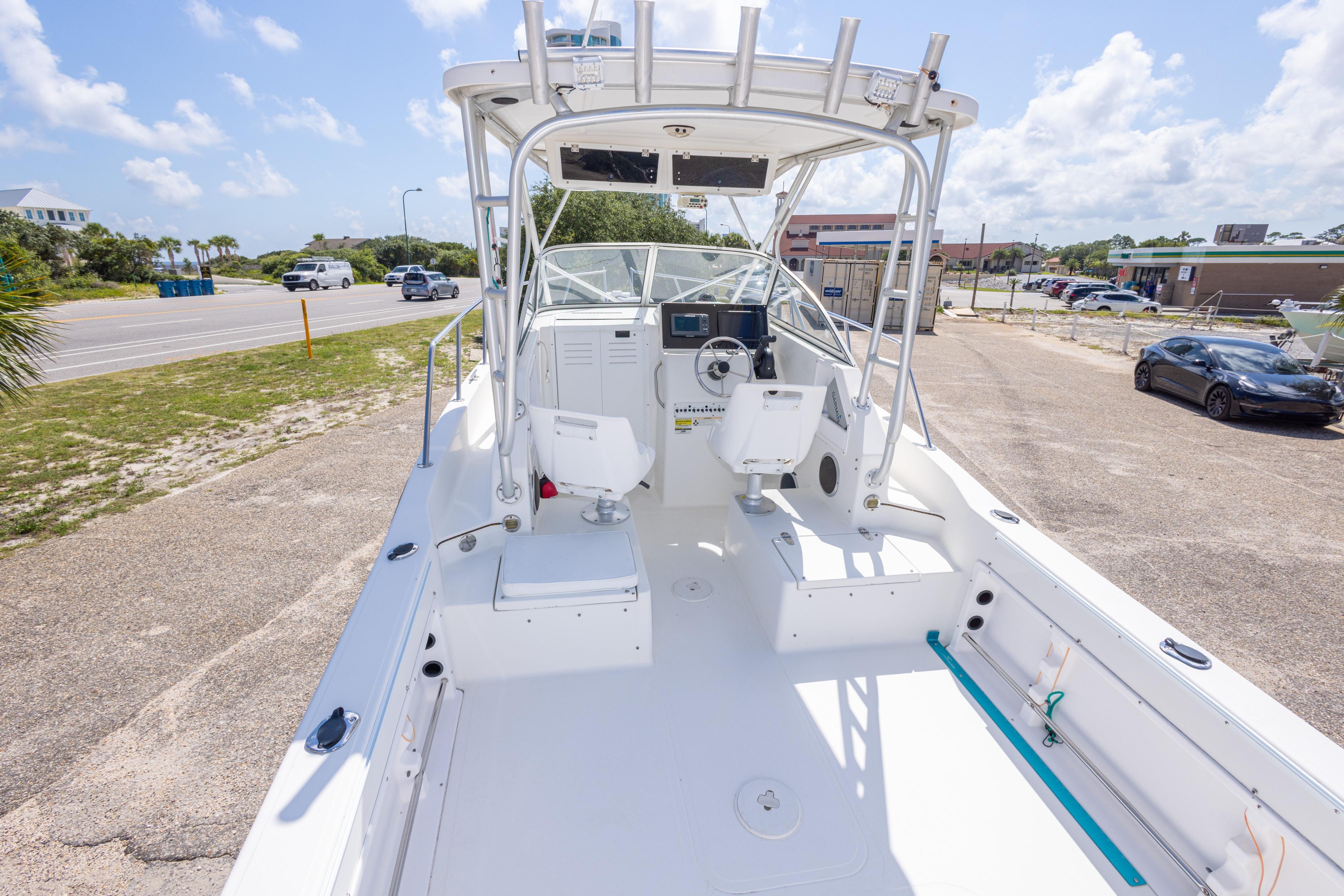 2007 Sea Boss 235 Walkaround boat with spacious deck and dual seating, parked near a road.