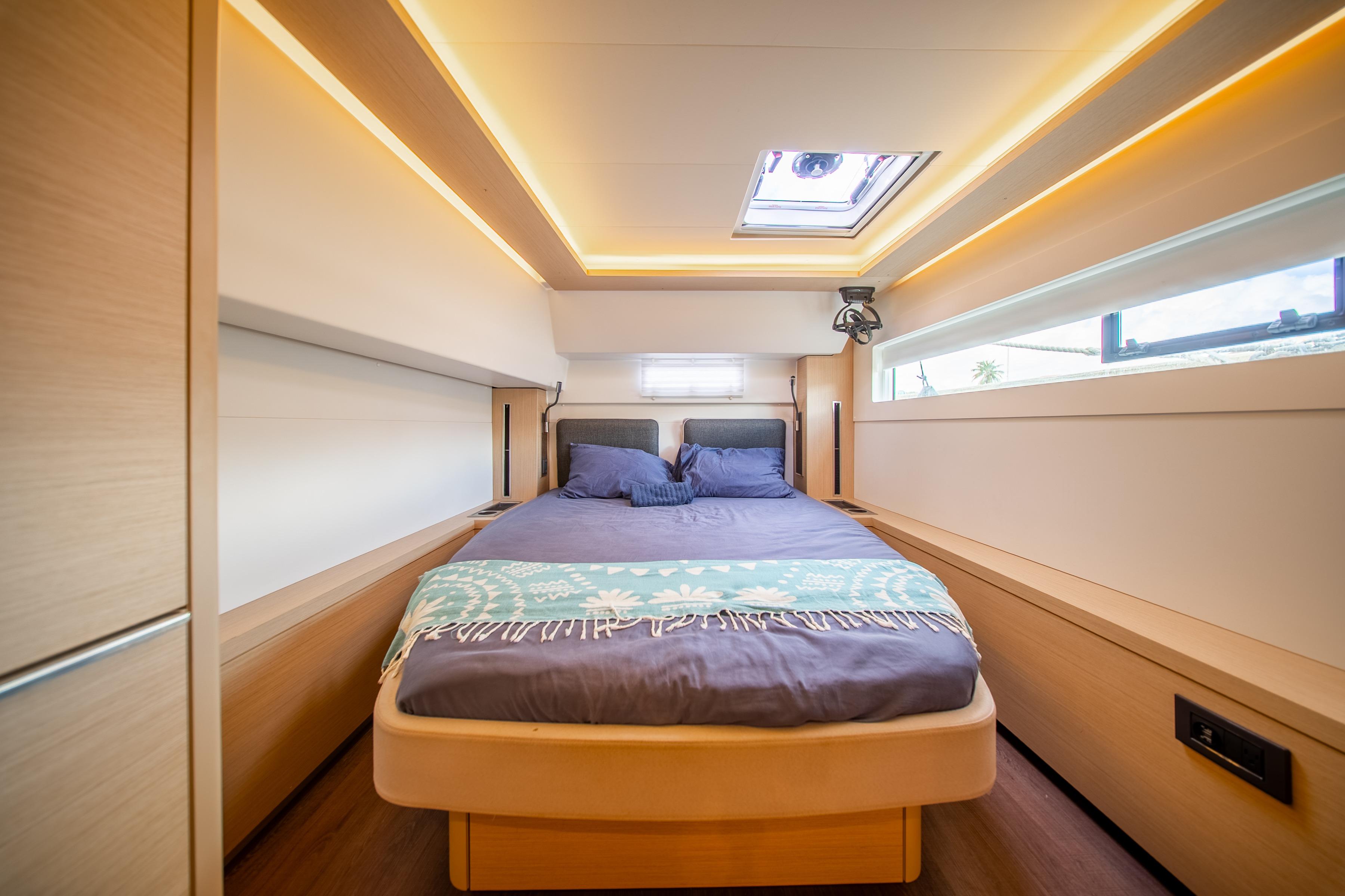 Luxurious cabin interior of 2023 Lagoon 46 yacht with modern design and cozy bedding.