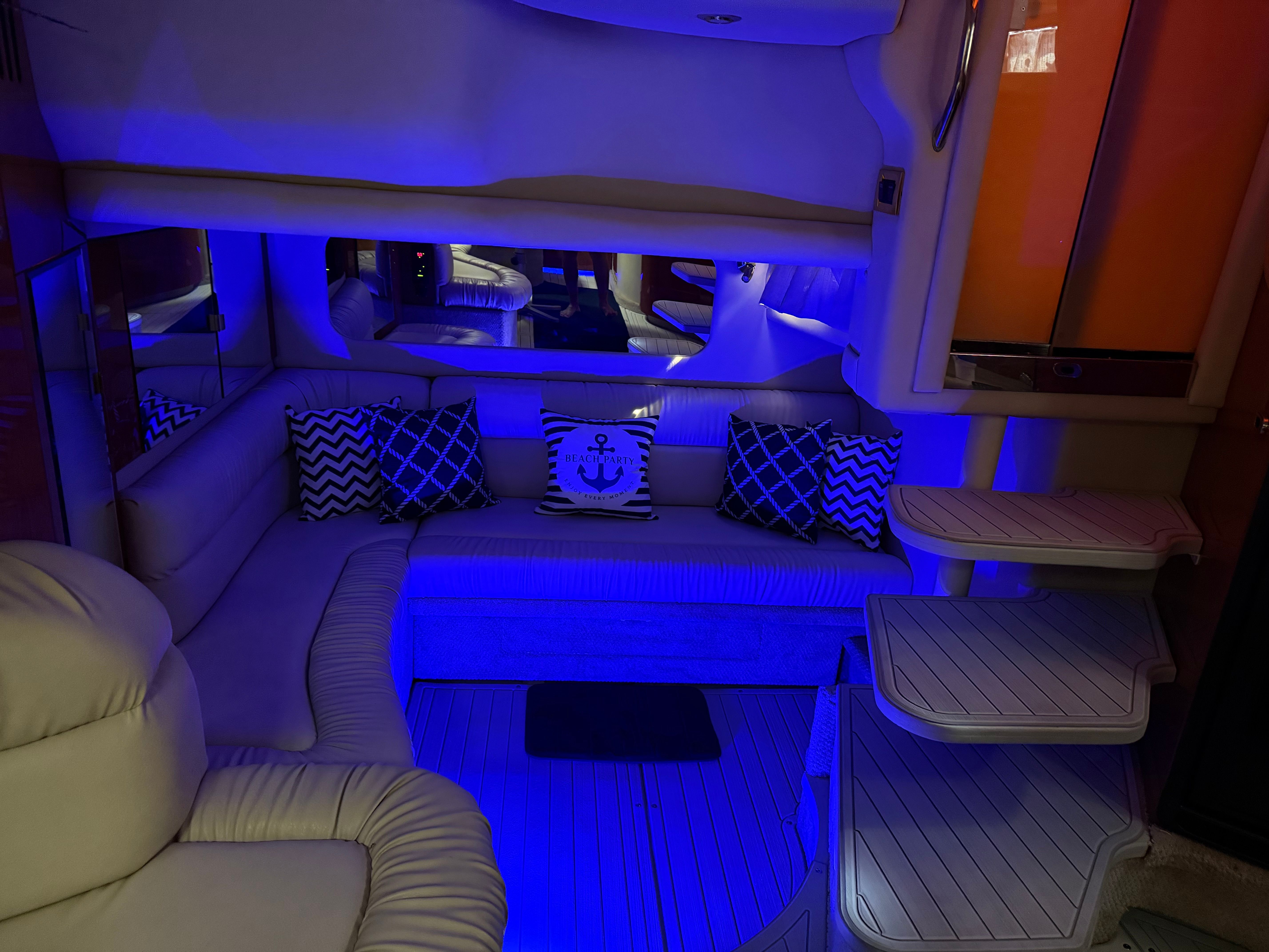 Interior of a Sea Ray 380 Sundancer with blue lighting and cozy seating.