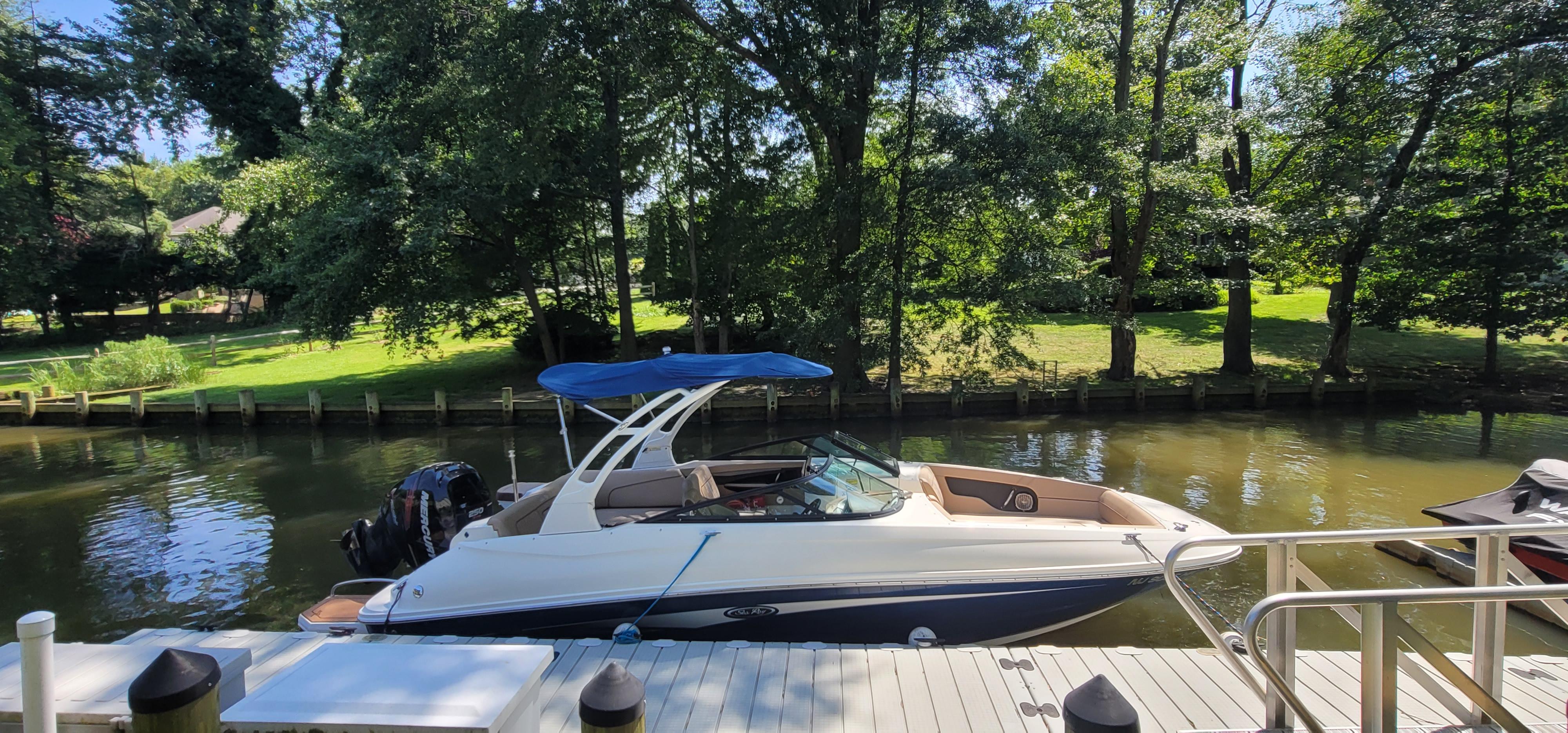 2017 Sea Ray SDX 240 Outboard boat docked by a scenic, tree-lined canal.