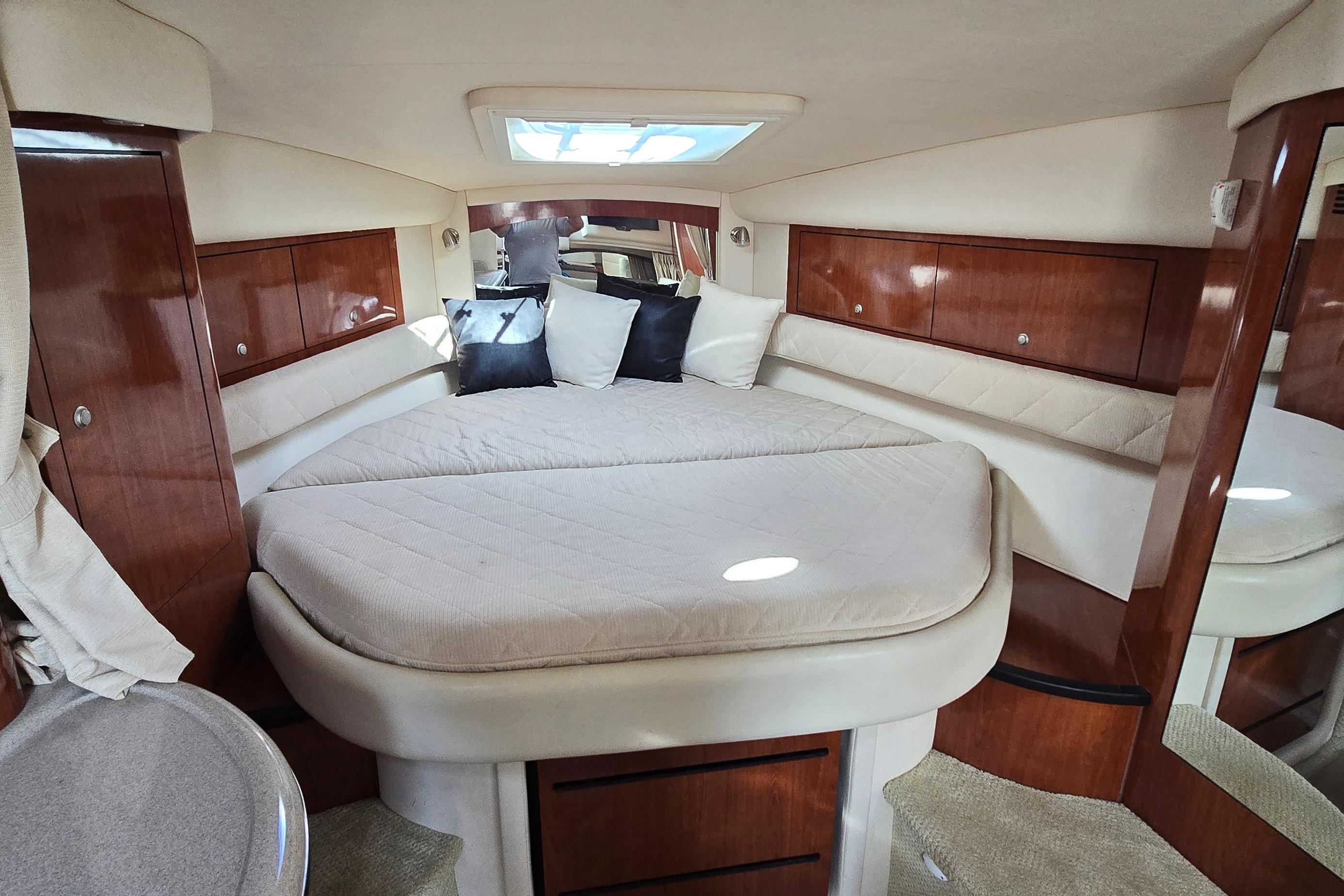 Luxurious cabin interior of 2007 Sea Ray 340 Sundancer with cozy bedding and wood accents.