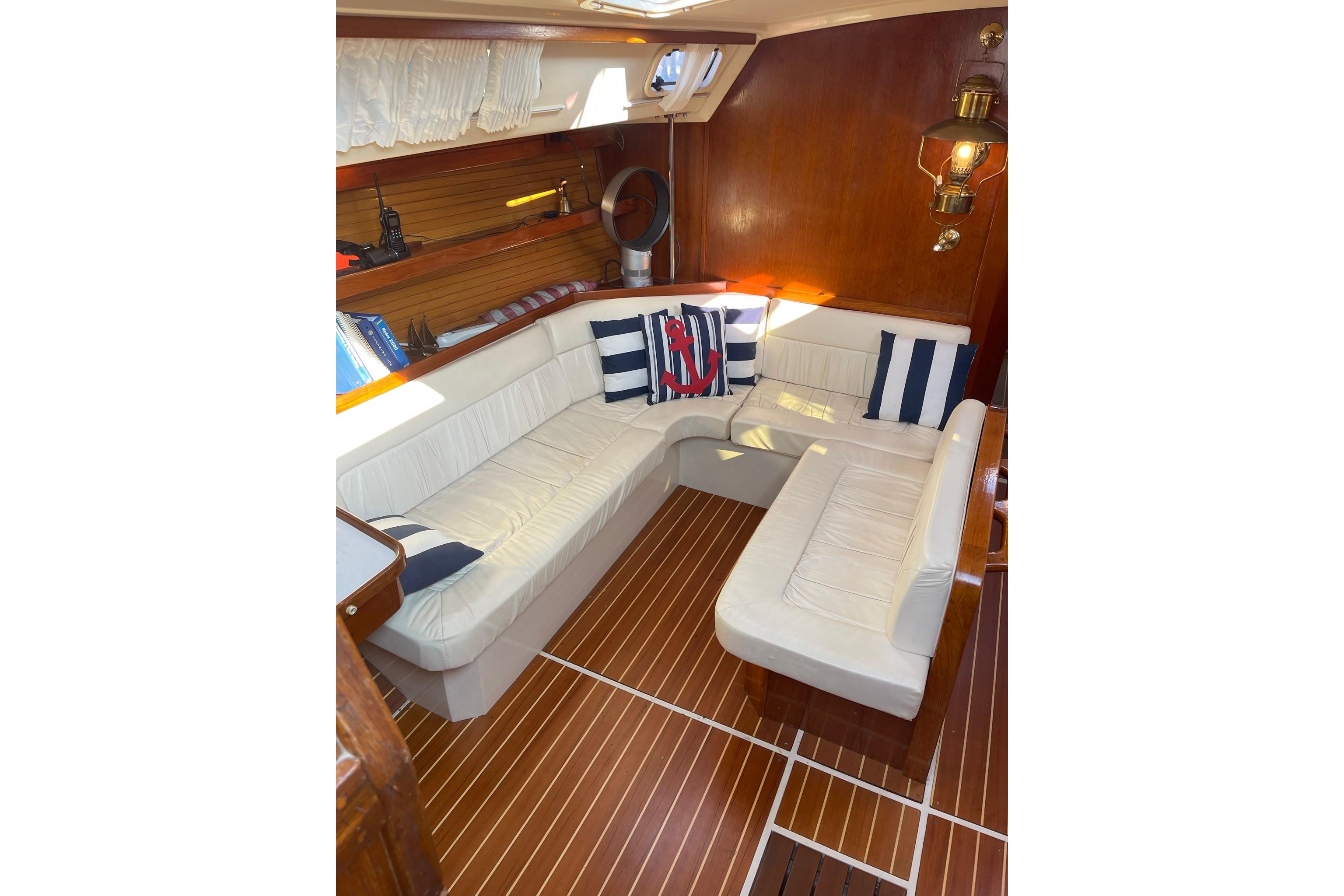 Interior of 1990 Catalina 42 yacht with white seating and nautical decor.