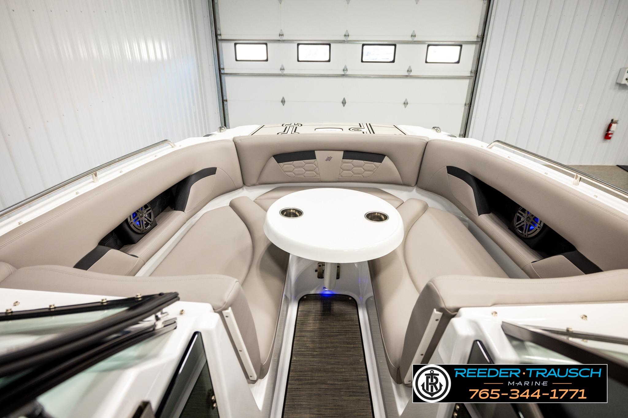2024 FOURWINNS HD5 Surf boat interior with beige seating and round table.