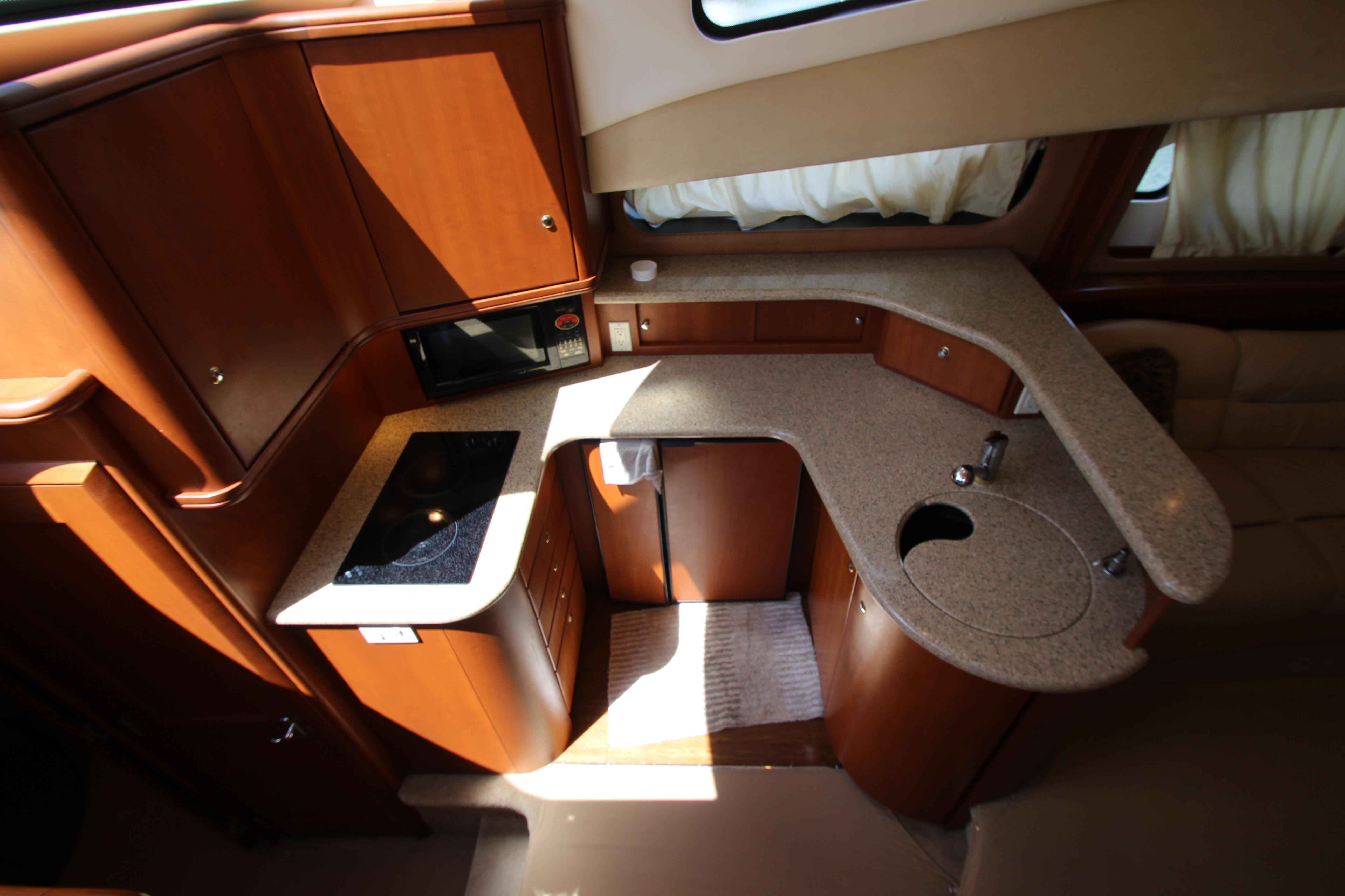 Interior of 2006 Silverton 38 Sport Bridge yacht kitchen with wood cabinetry and countertops.