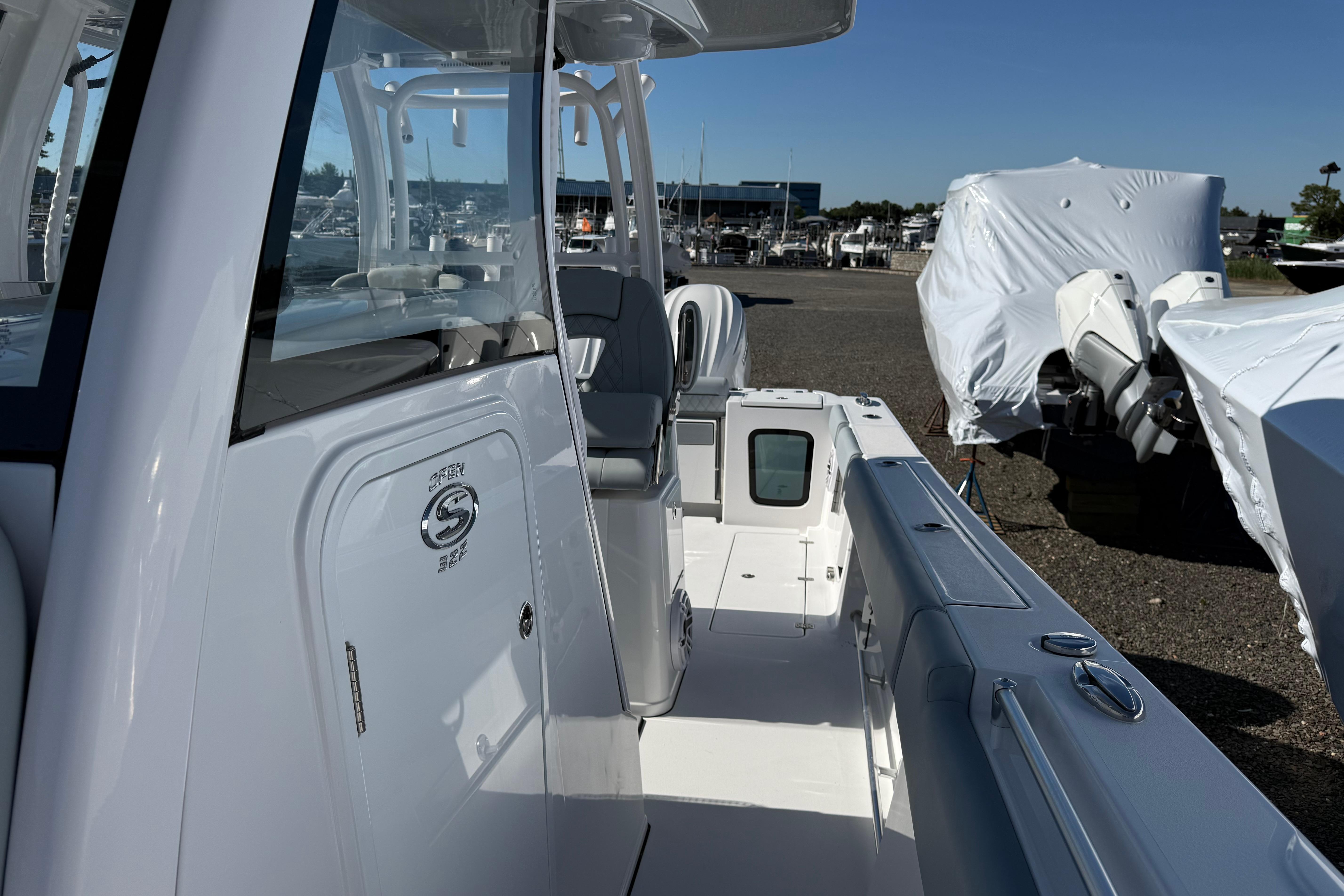 2026 Sportsman Open 322 Center Console boat, docked with covered vessels in the background.