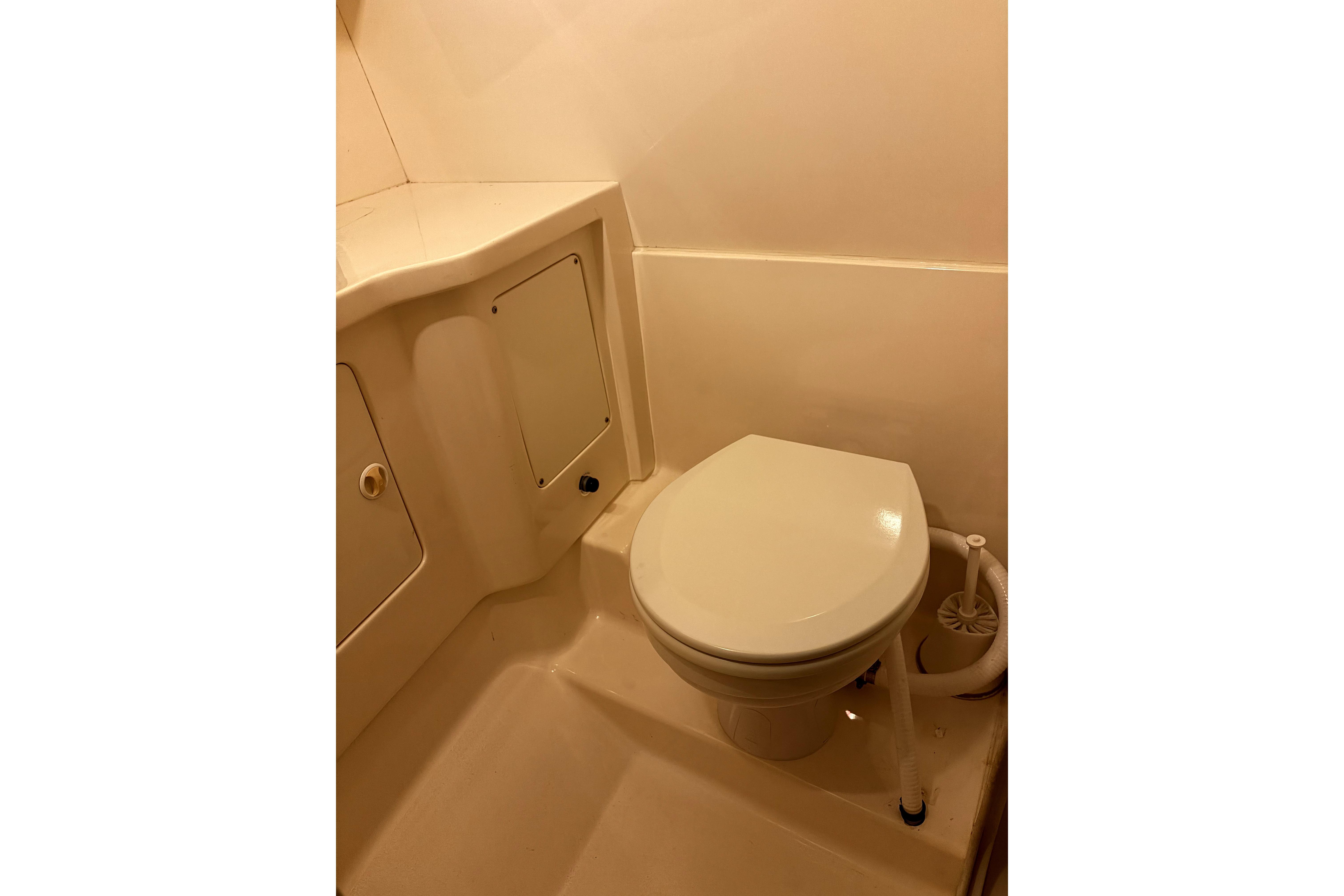 Compact bathroom in a 1998 Intrepid 339 Walkaround boat, featuring a marine toilet.