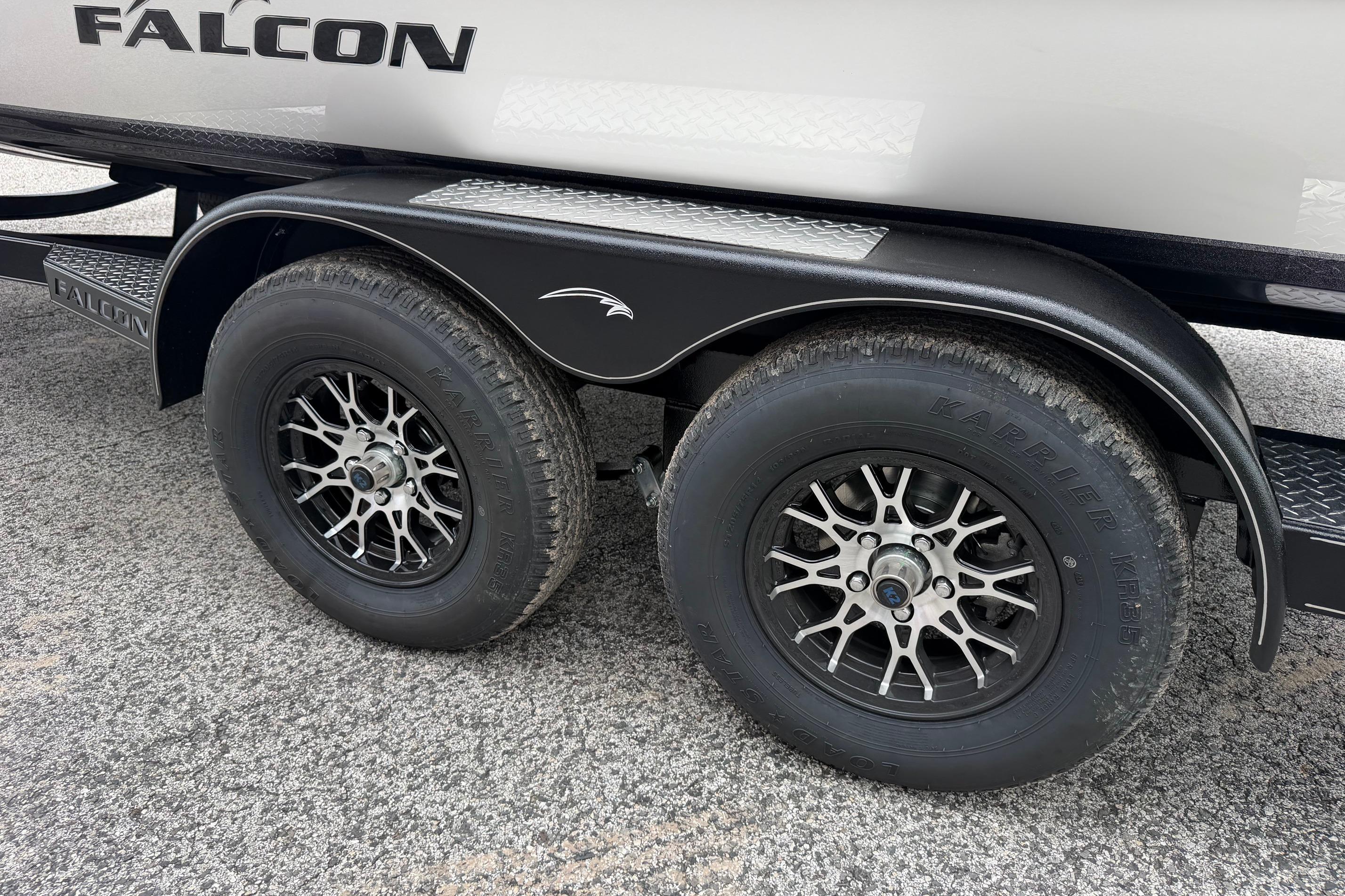 Trailer wheels of a 2027 Falcon Boats F215 on a textured surface.