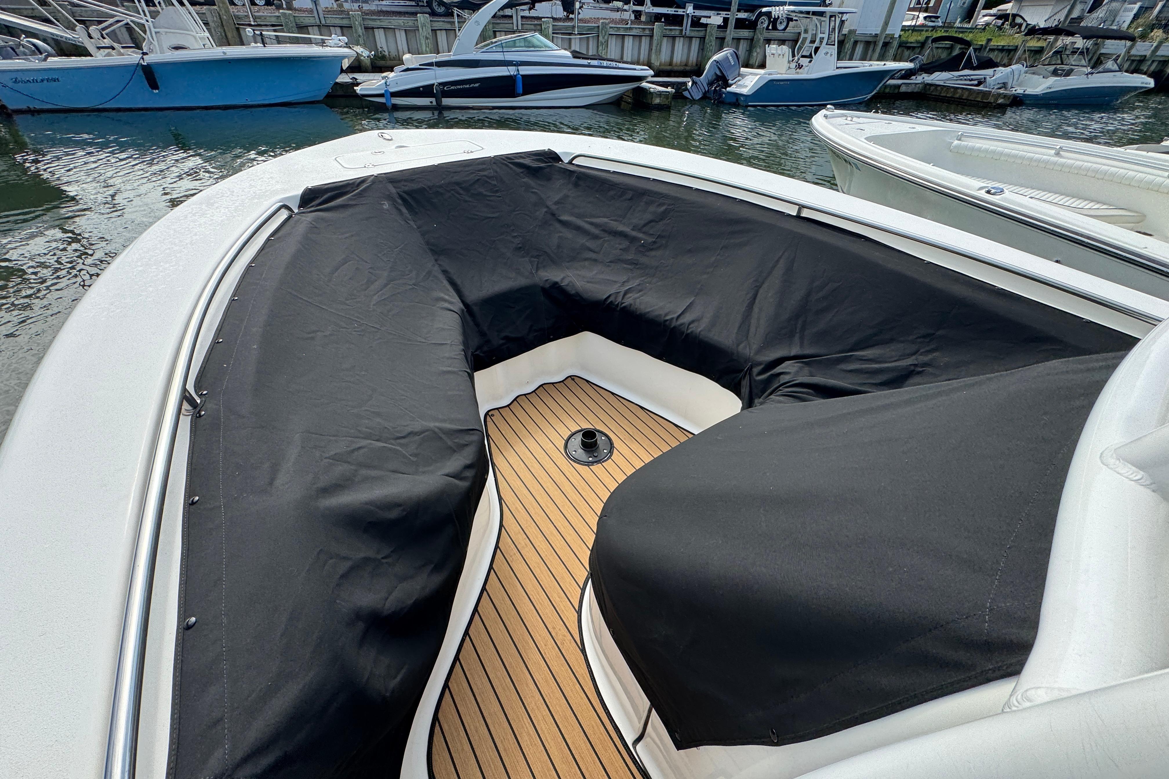 2016 Tidewater 230 LXF boat with black covers and teak deck, docked at marina.