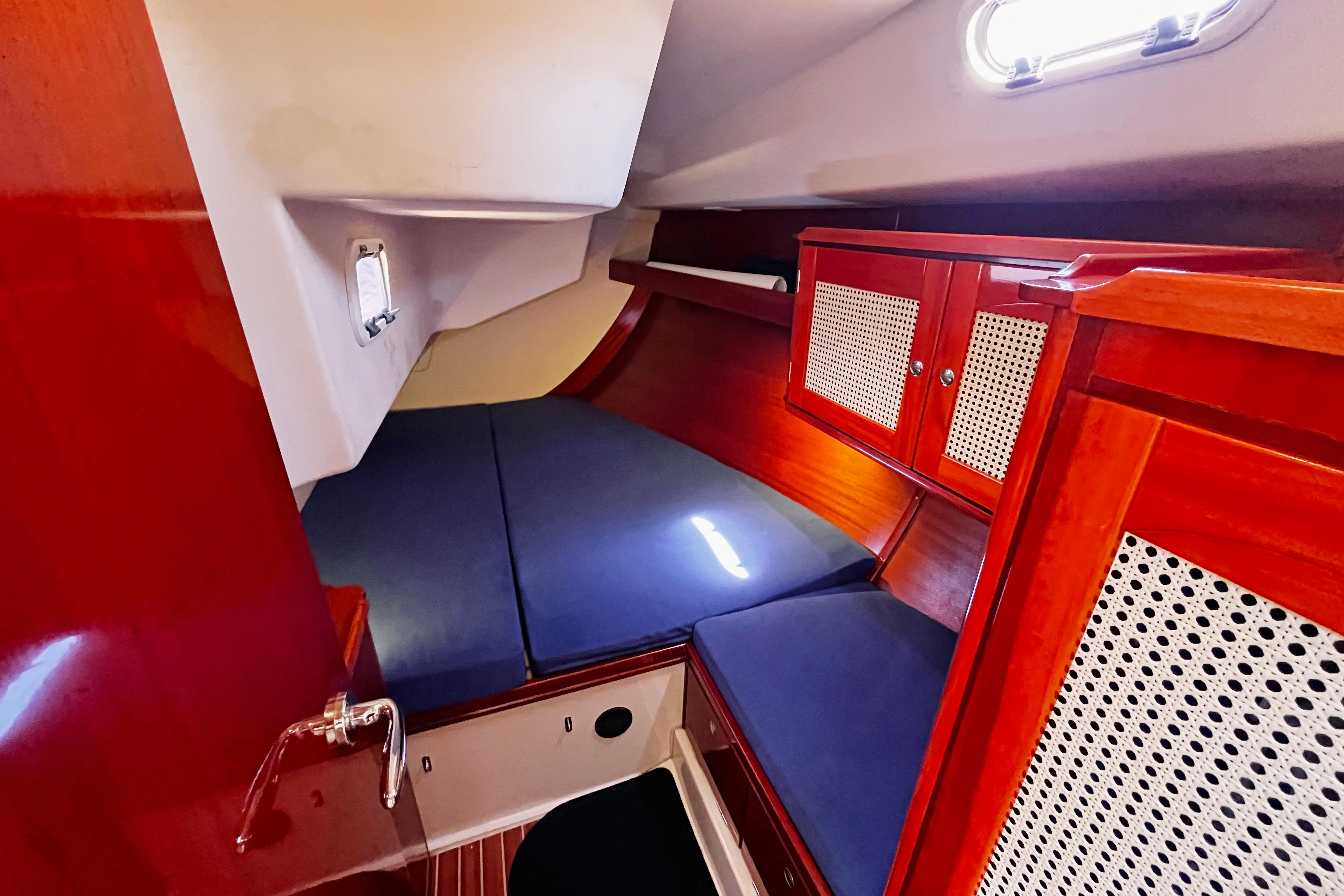Cozy cabin interior of 2004 Hanse 411 yacht with wooden cabinetry and blue cushions.