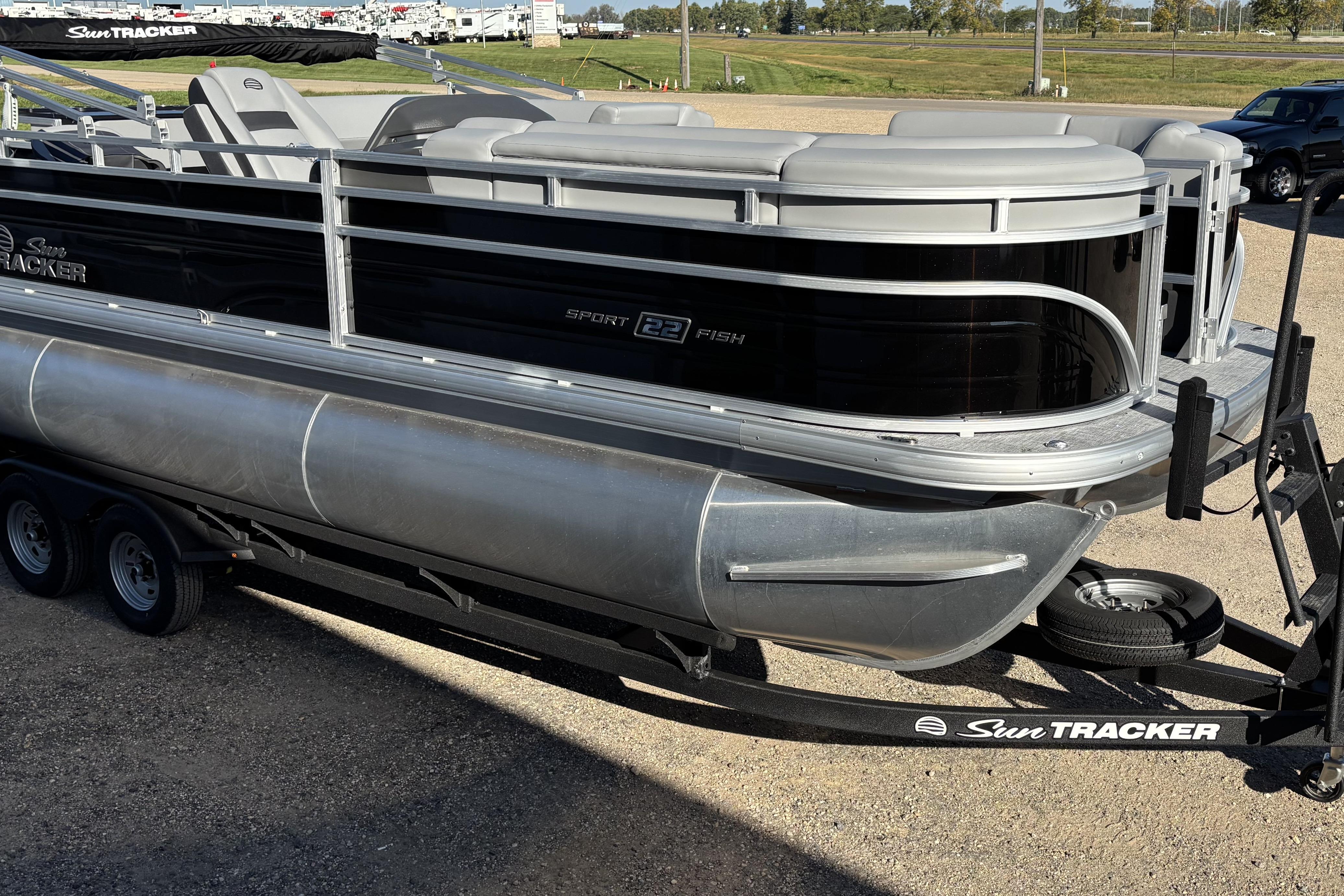 2026 Sun Tracker SportFish 22 XP3 pontoon boat on trailer, parked outdoors.