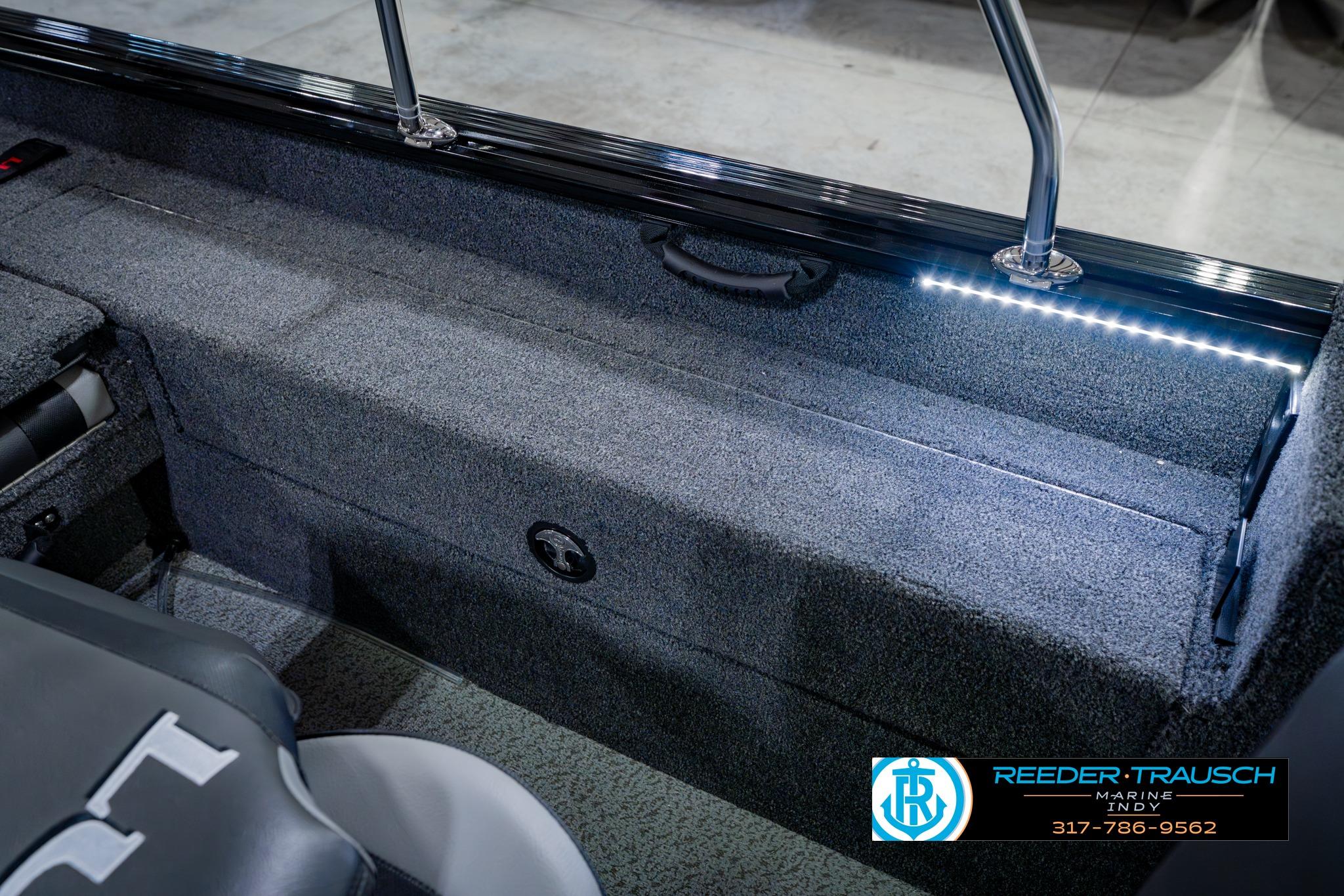 2026 Lund 1875 Impact XS boat interior with LED lighting and carpeted storage area.