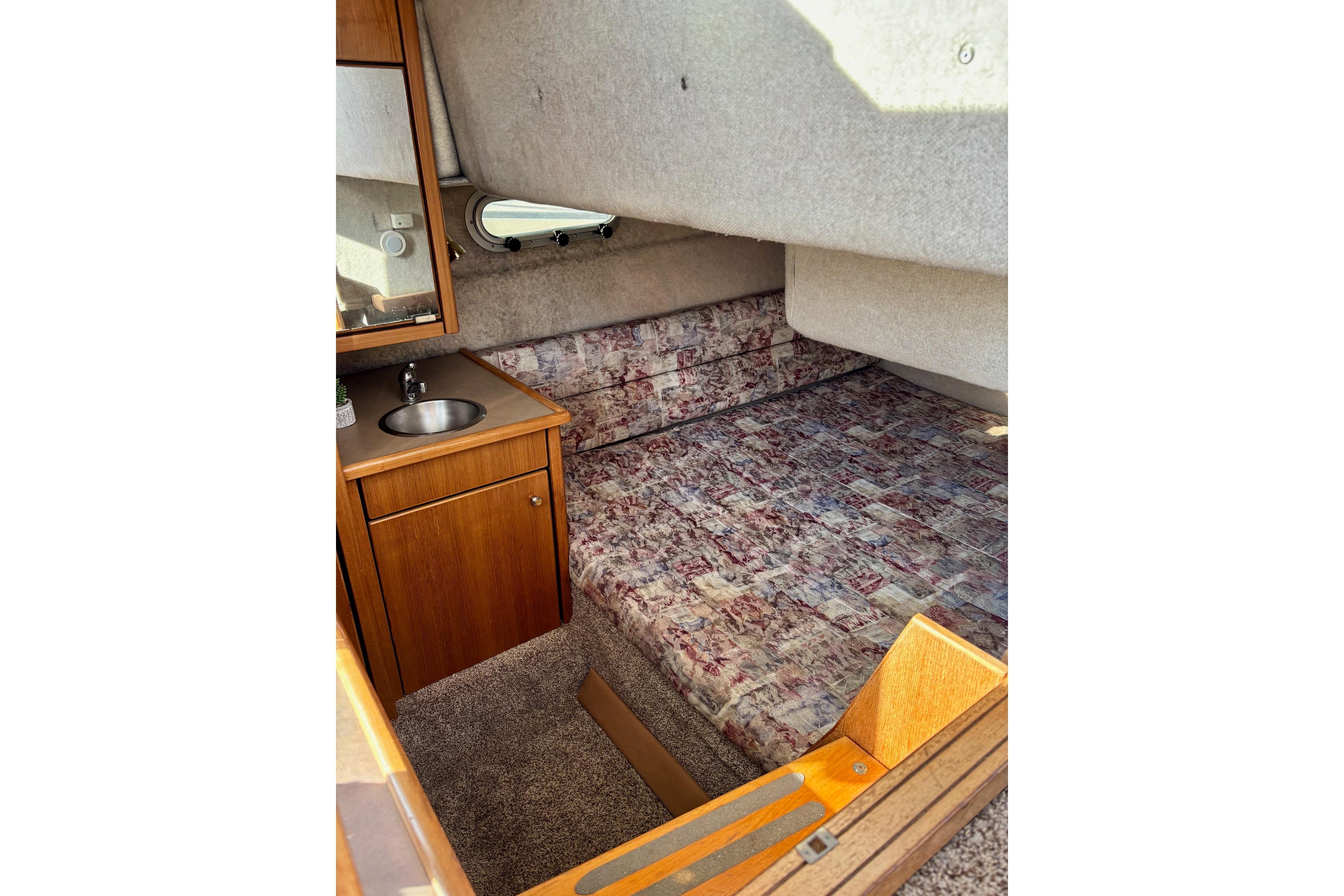 1998 Bayliner 3388 Command Bridge Motoryacht cabin with bed, sink, and wooden cabinetry.