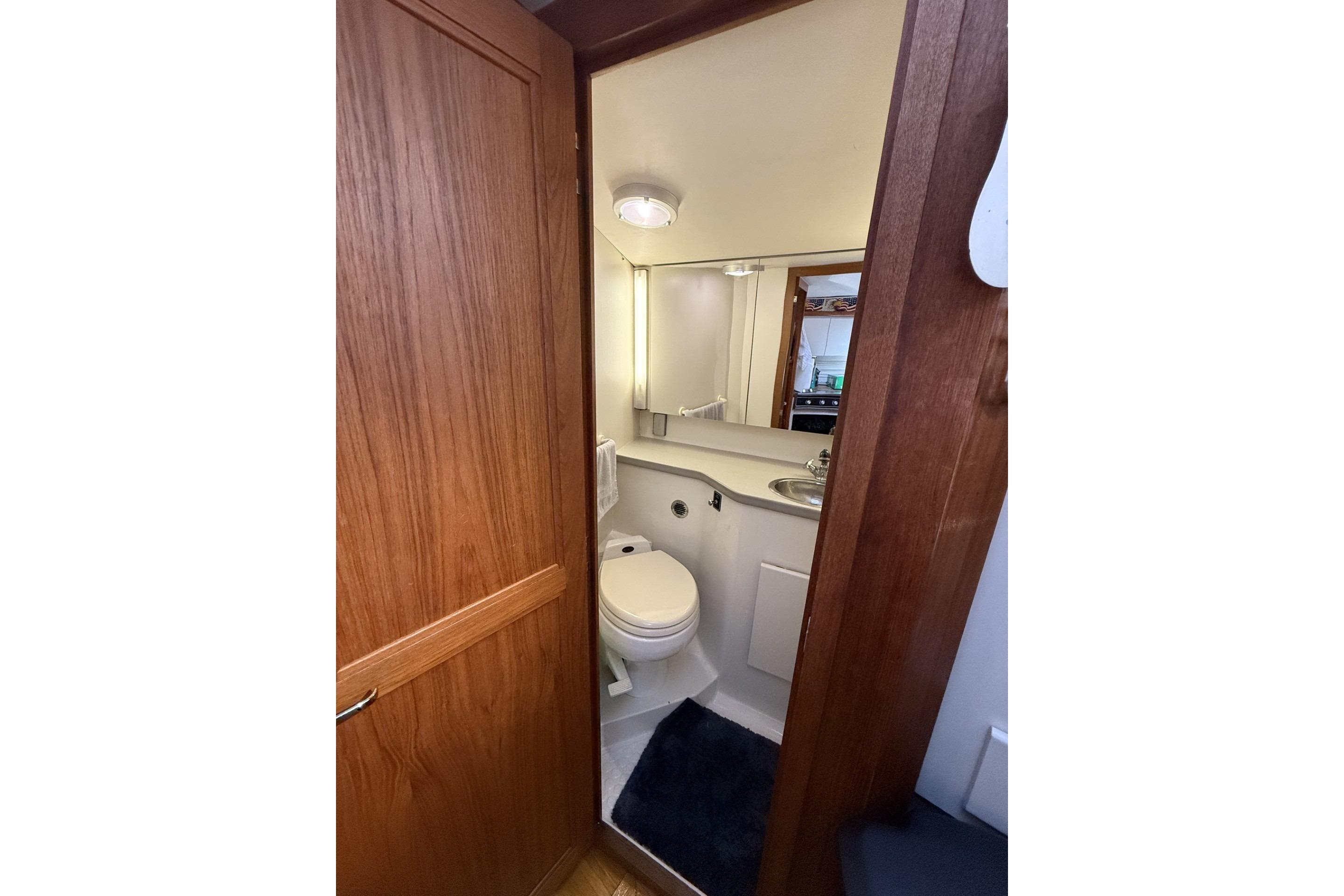 Bathroom interior of 1993 Carver 350 Motor Yacht with wooden door and compact design.