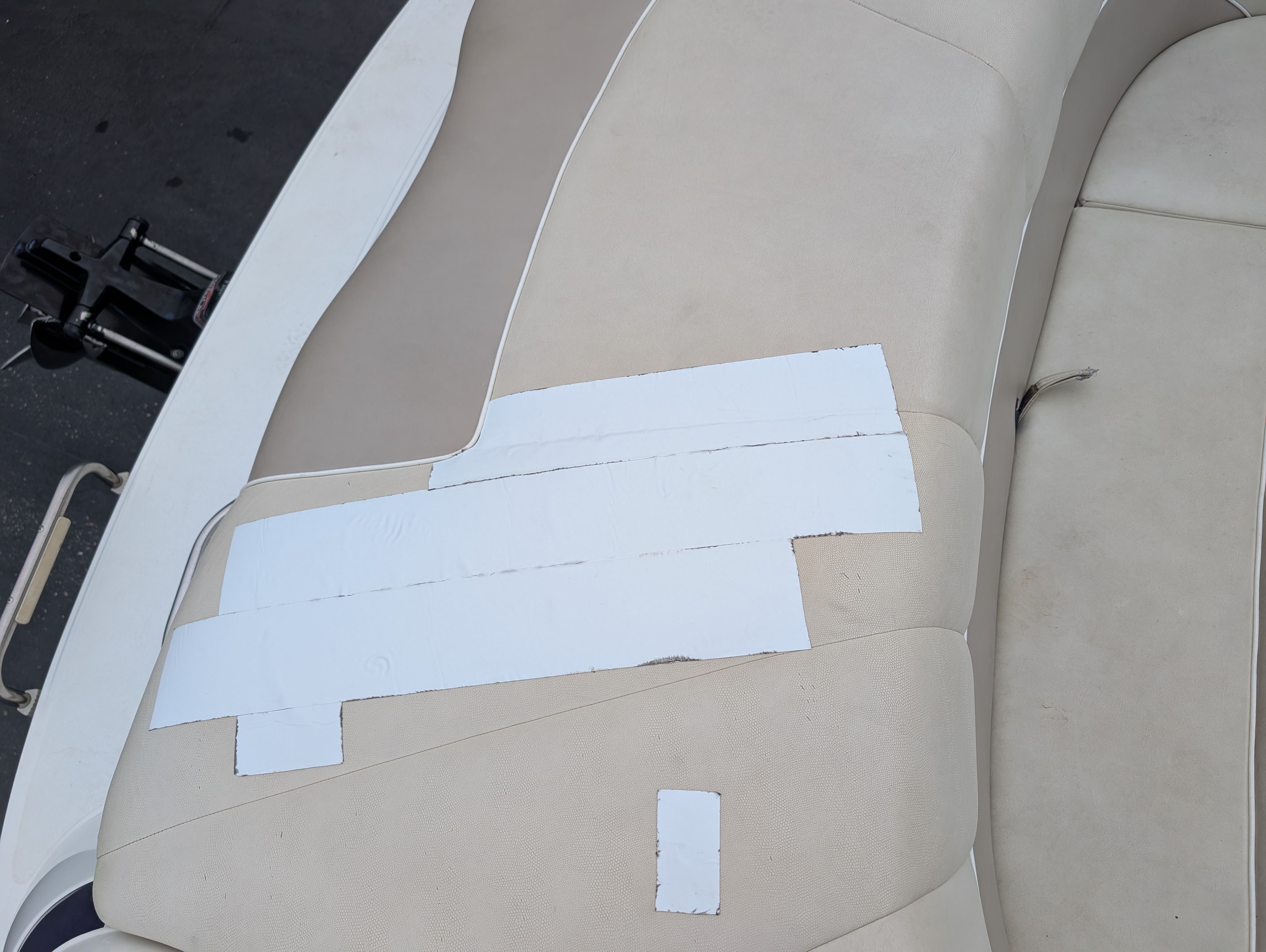 Close-up of a beige boat seat with white repair tape strips.