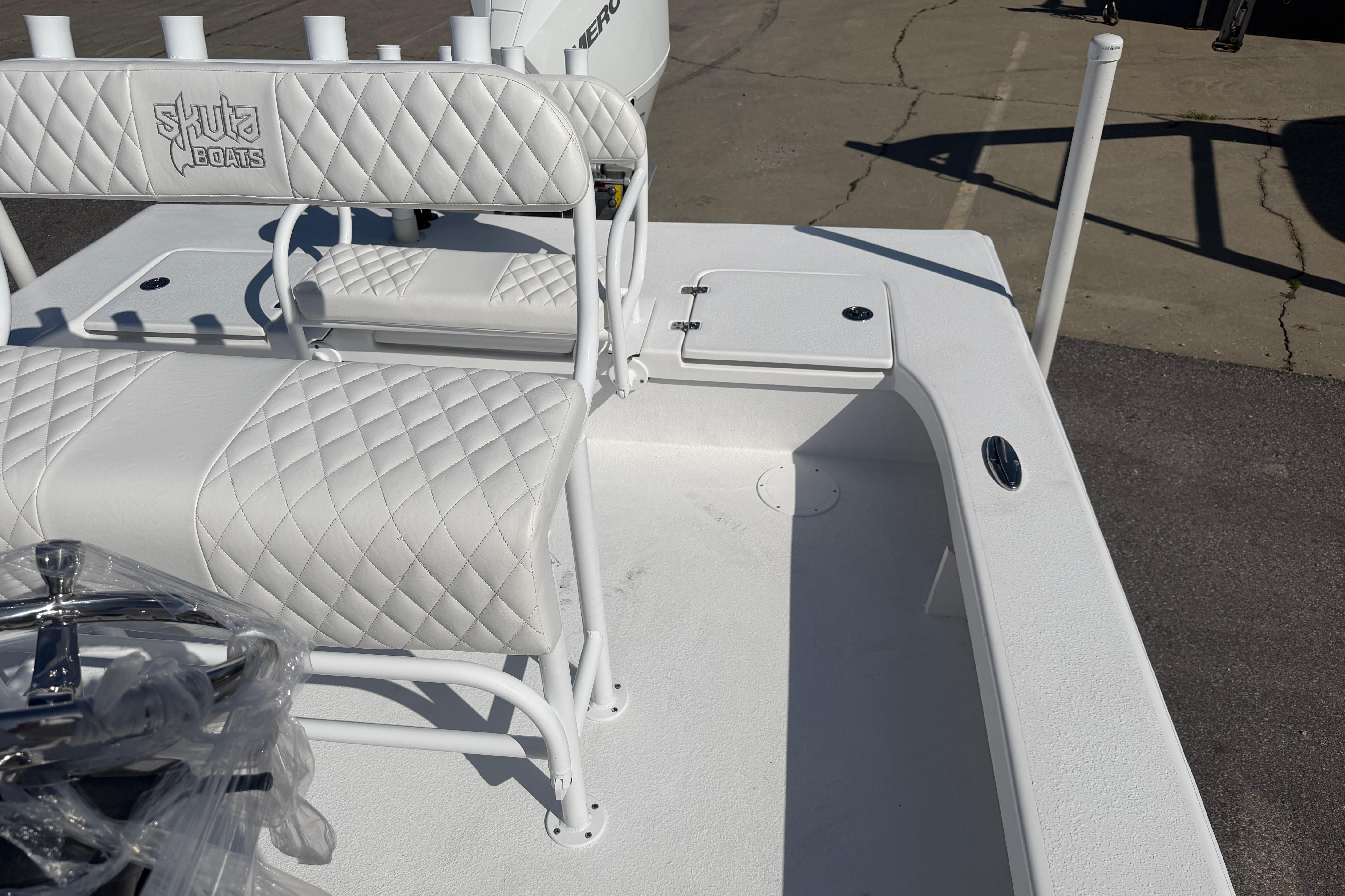 2026 Skuta 24 Cat boat interior with quilted white seating and storage compartment.