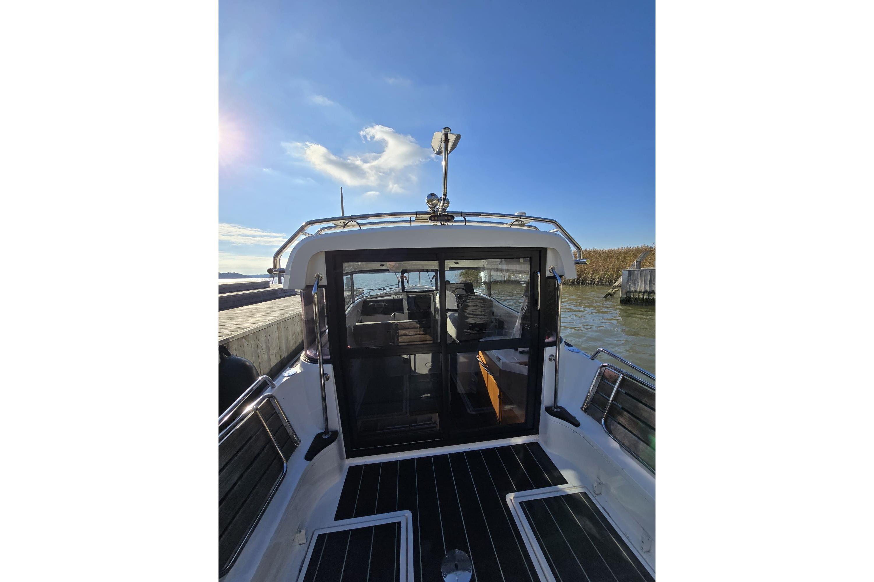 2016 XO Boats 270 RS docked, showcasing rear deck and cabin under clear blue sky.