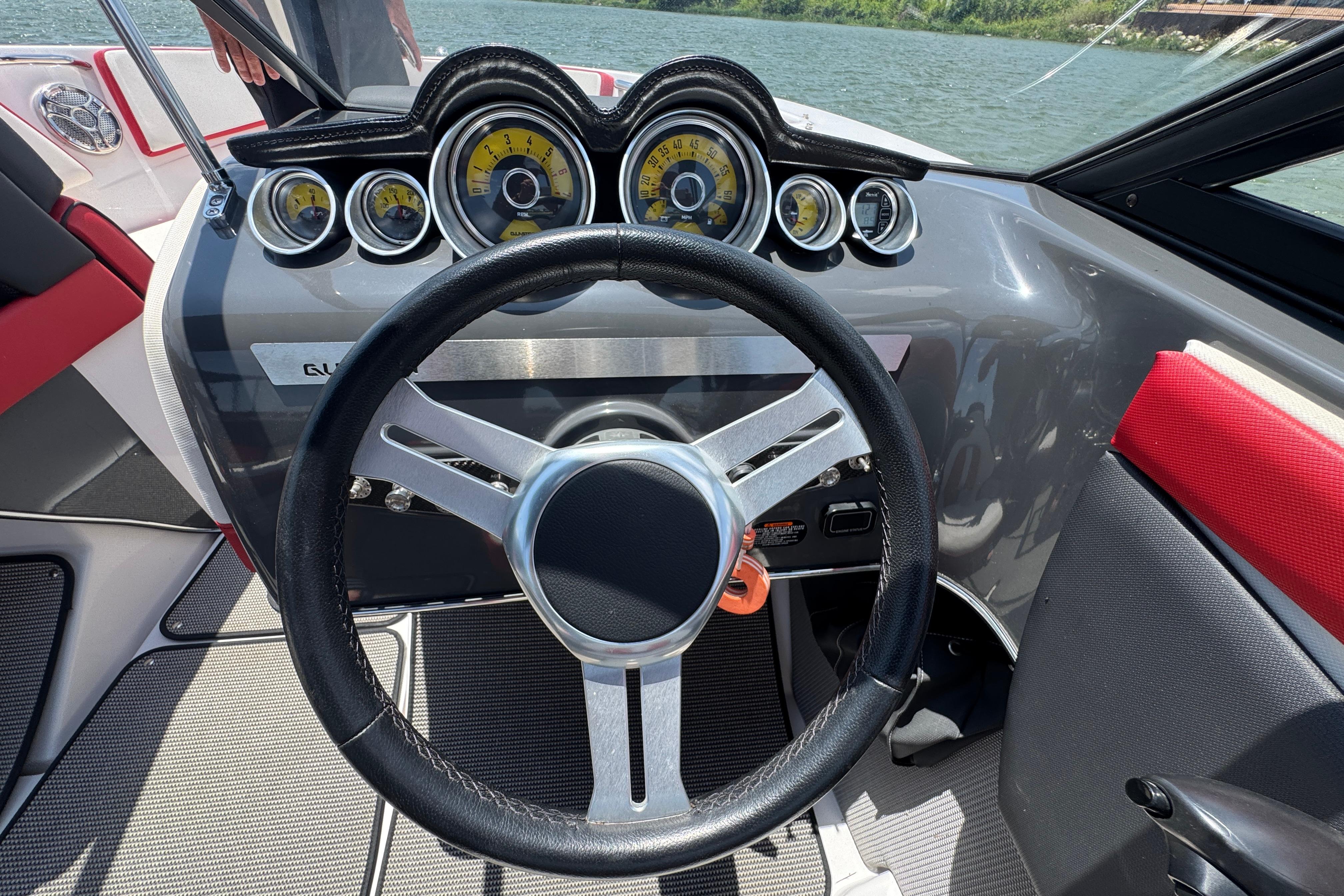 Steering wheel and dashboard of a 2017 Glastron GT 225 boat on water.