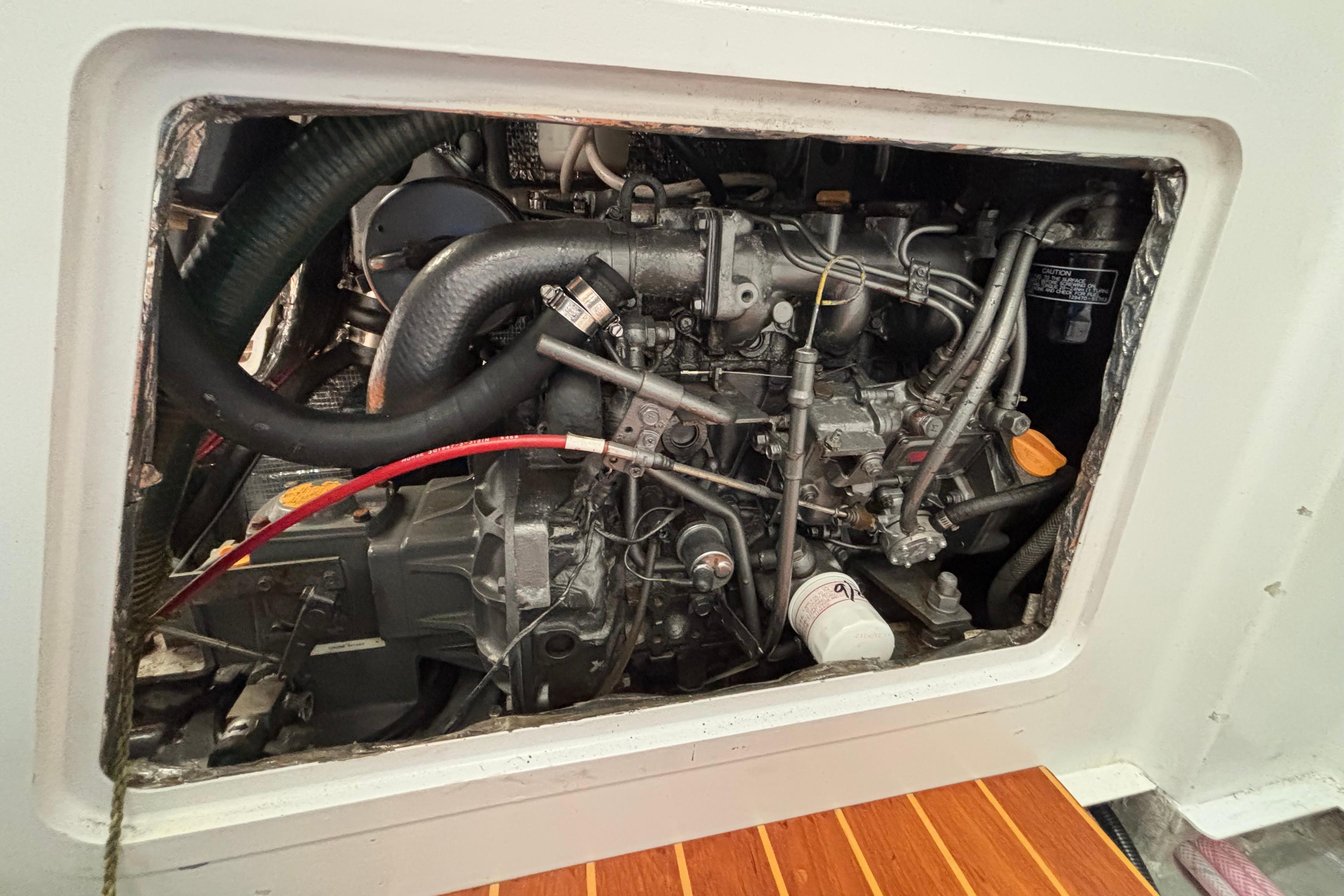 Engine compartment of a 1995 Tripp 47 sailboat, showcasing mechanical components and hoses.