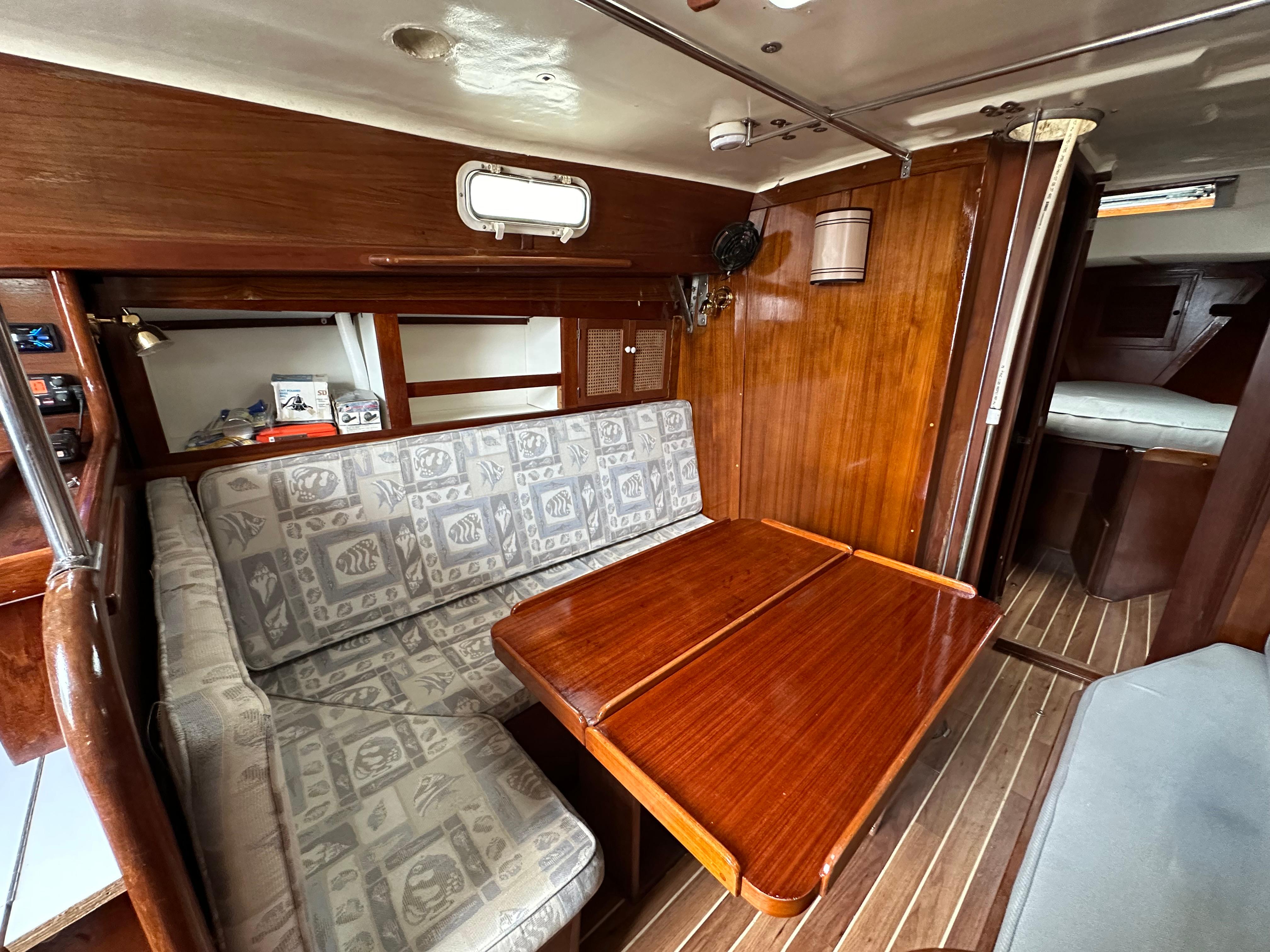 Interior of 1981 Tartan 37 sloop with wooden table and patterned seating.