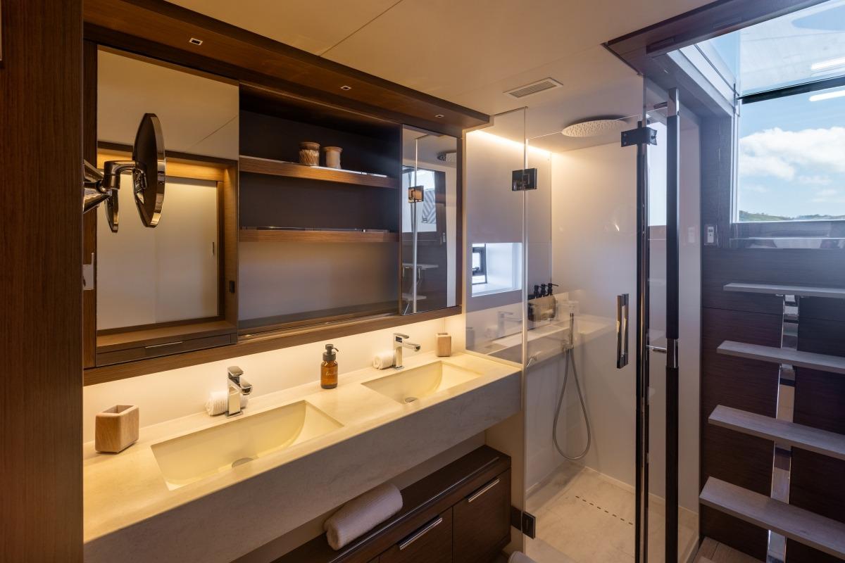 Luxurious bathroom interior of 2020 Lagoon Sixty7 yacht with dual sinks and glass shower.