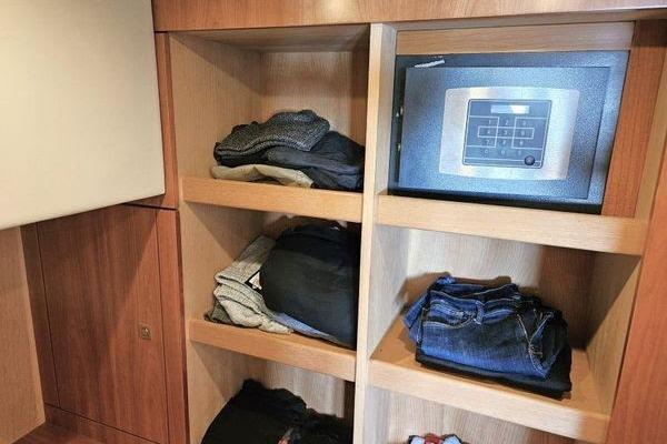 Wooden closet with clothes and a safe inside a 2005 Sunseeker Manhattan 66 yacht.