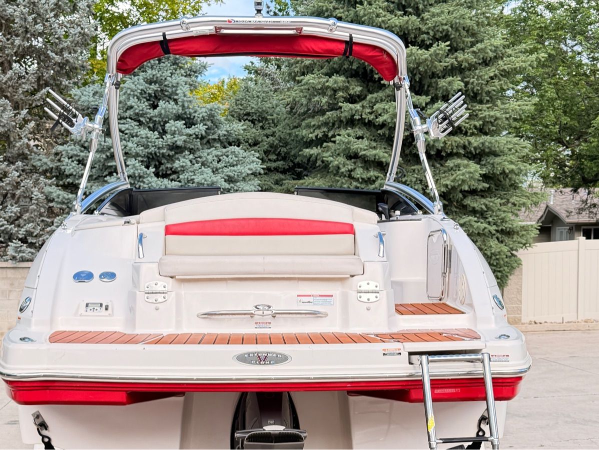 A 2008 Chaparral Sunesta 224 with a red sunshade and wooden deck, surrounded by trees.