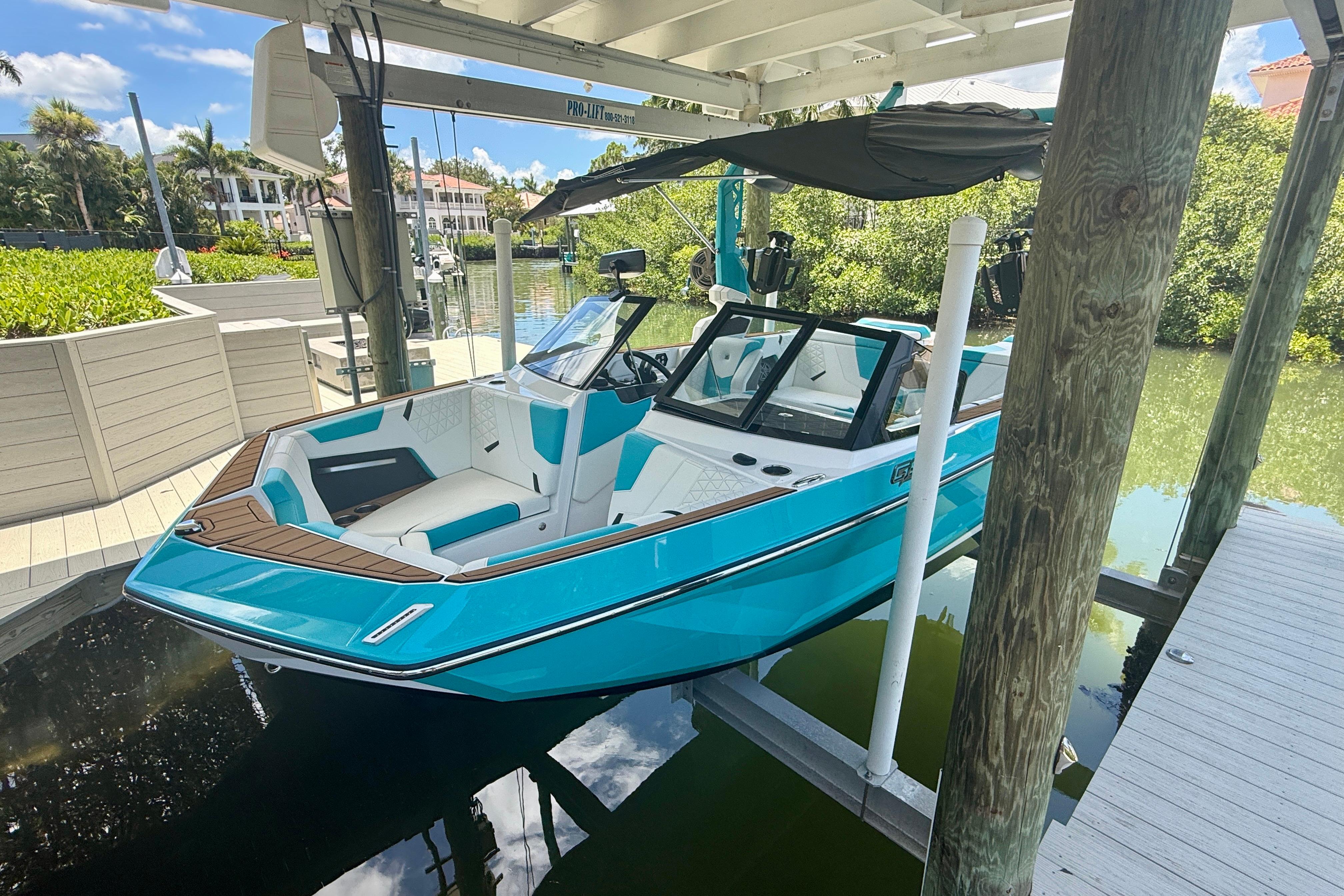 2024 Nautique Super Air Nautique GS20 boat docked under a canopy, vibrant blue exterior.