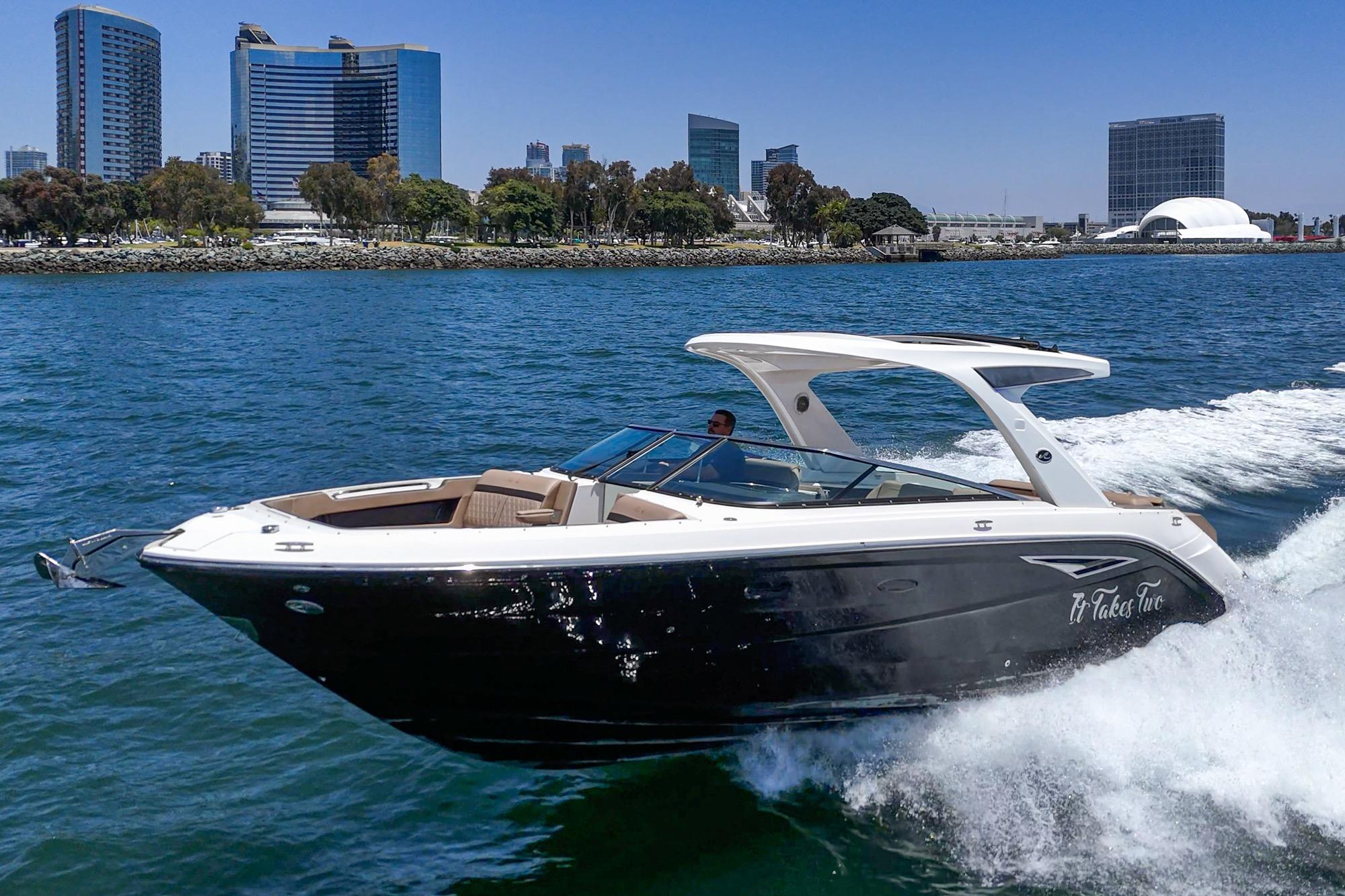 2018 Sea Ray SLX 310 cruising on water with city skyline in background.