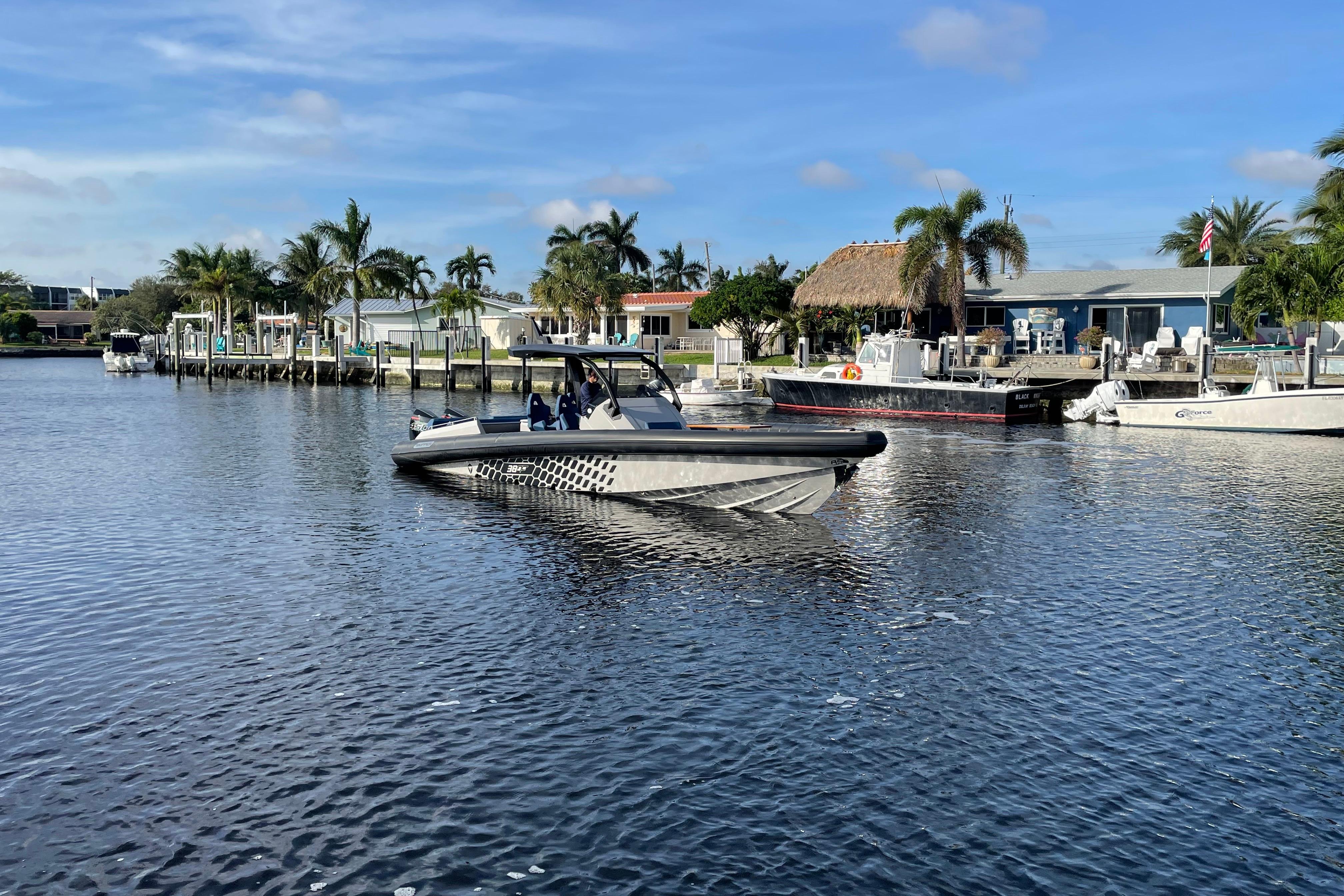 2023 Skipper-BSK BSK 38 boat cruising in a scenic waterfront area with palm trees.
