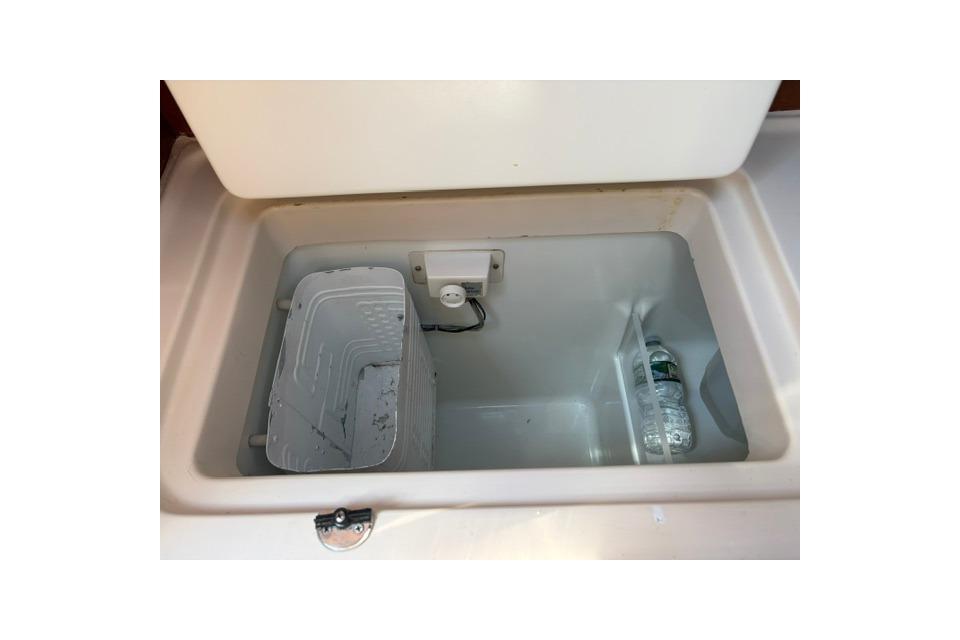 Storage compartment inside a 2000 Beneteau Oceanis 321 sailboat, featuring a water bottle.