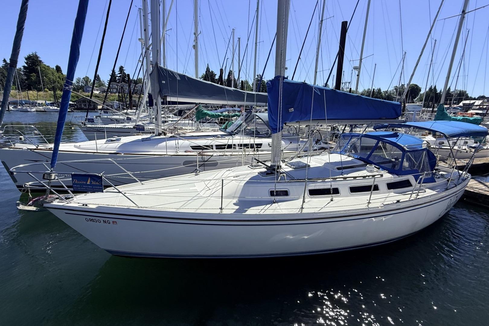 1985 Catalina 36 sailboat docked in a marina, featuring blue covers and clear skies.