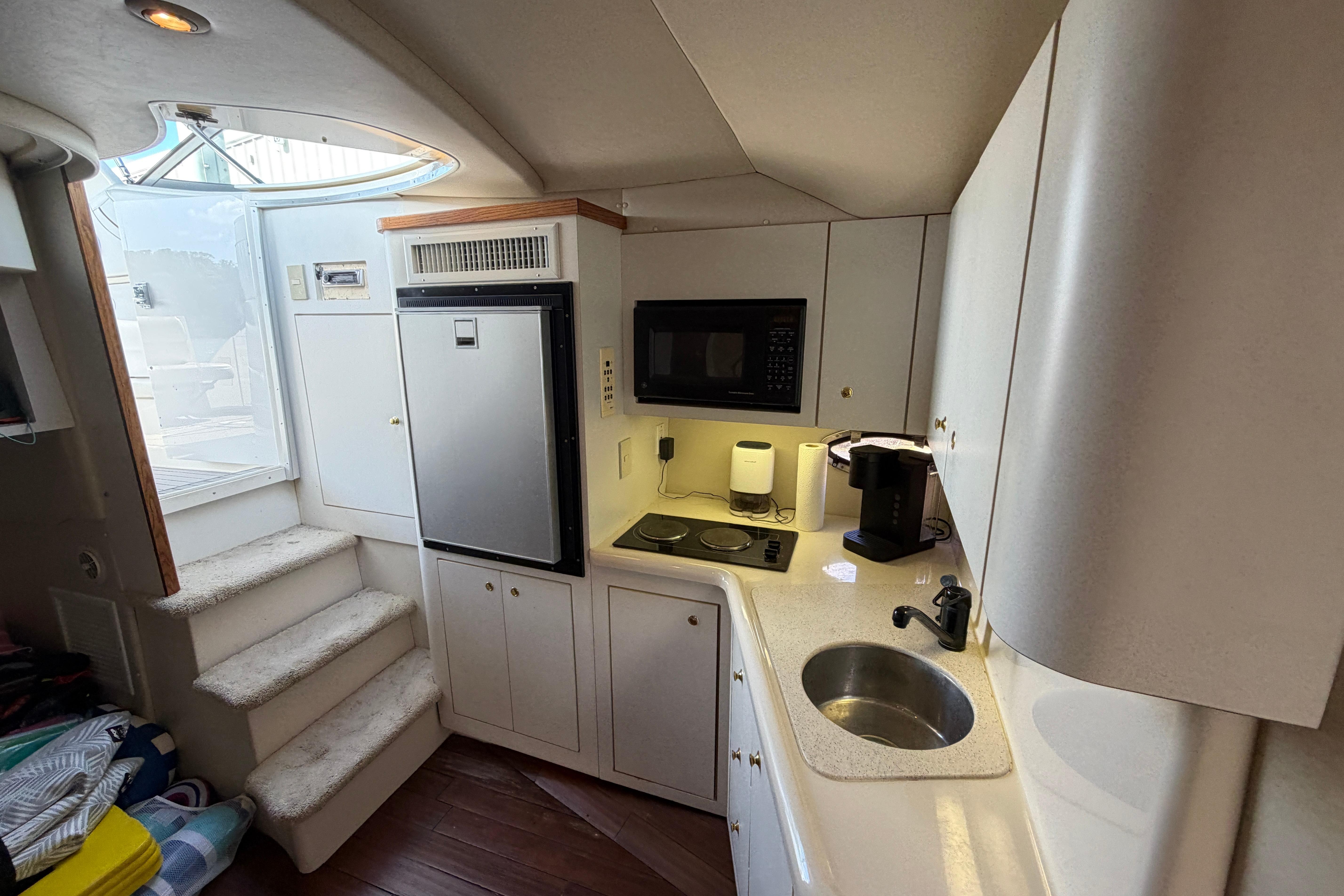 1997 Cruisers 3575 yacht kitchen with microwave, fridge, sink, and stairs to deck.