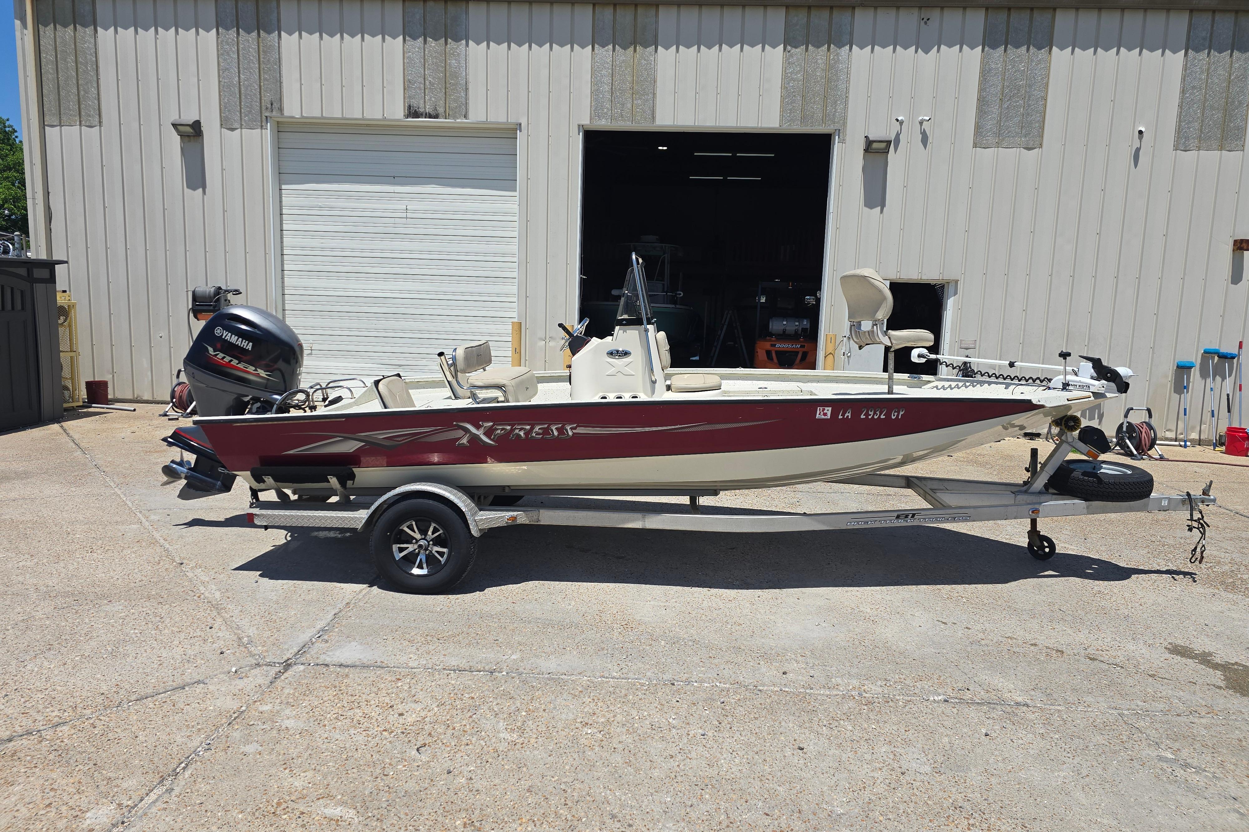2016 Xpress H20B Bay boat with Yamaha motor on trailer, parked outside a garage.