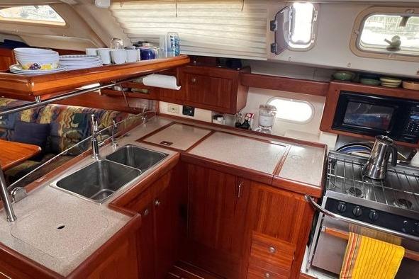 Interior of a 1999 Hunter 410 yacht kitchen with wooden cabinetry and modern appliances.