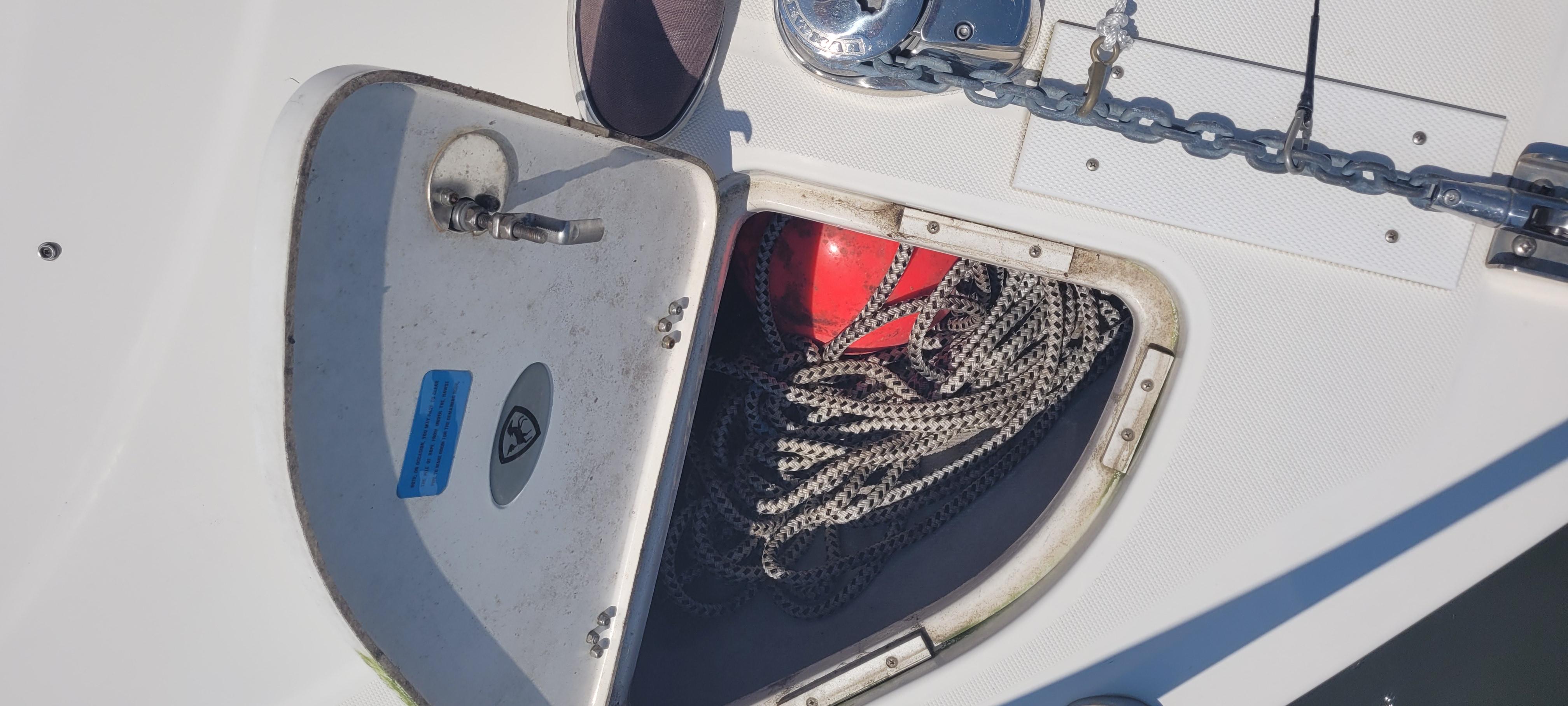 Open storage compartment on 2015 Century 30 boat with rope and red buoy.