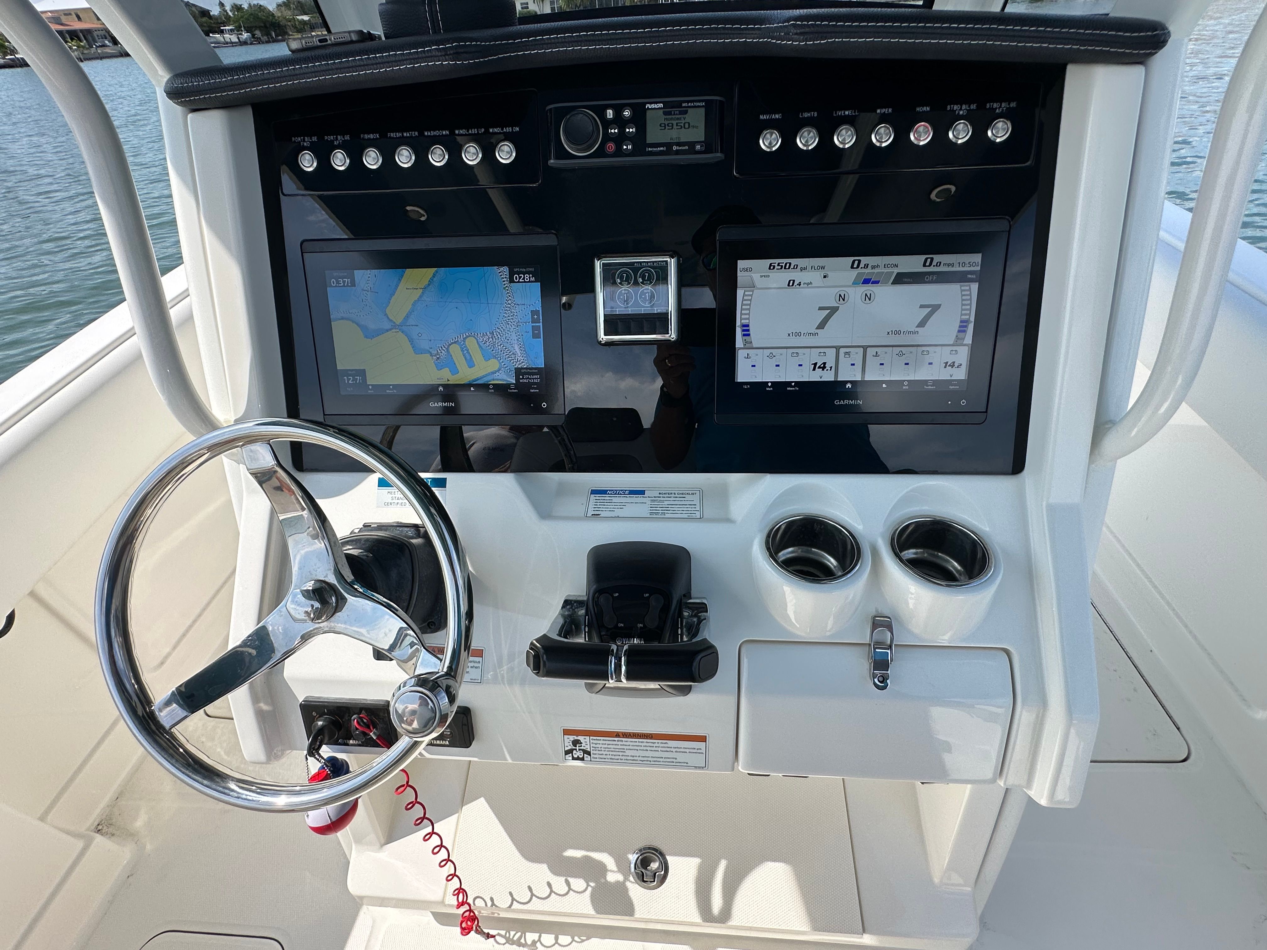 The image shows a boat's helm with two large screens and a steering wheel.