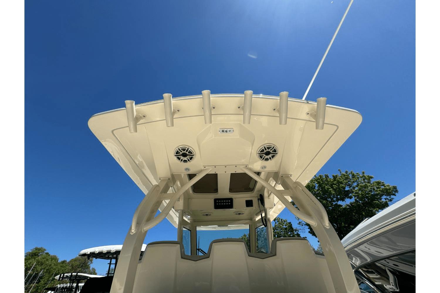 2024 Scout 357LXF boat roof with rod holders and speakers under clear blue sky.
