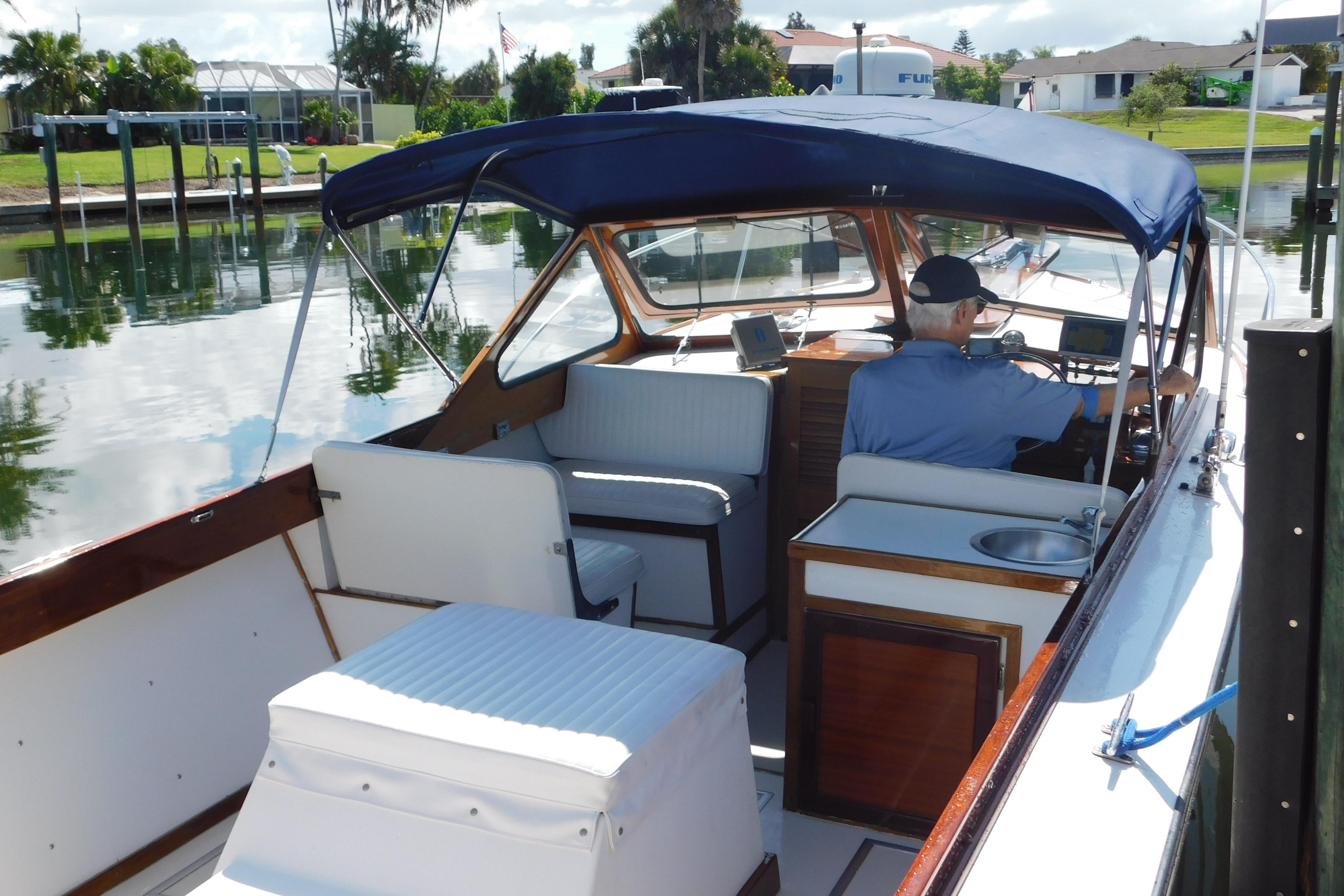 1995 Lyman 27 Cruisette boat with canopy, docked in a serene waterfront setting.