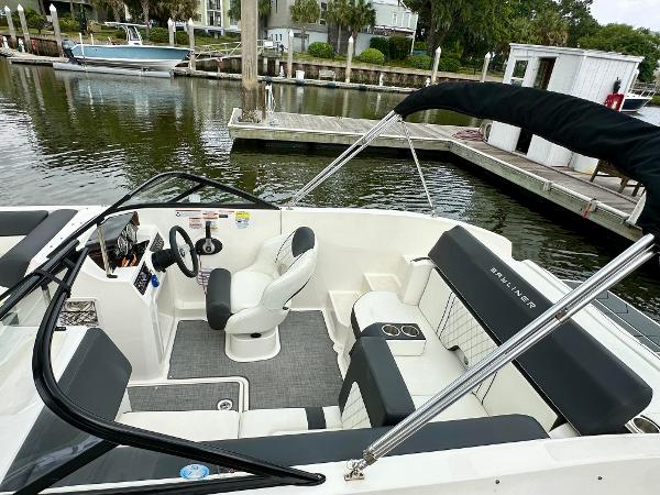 2022 Bayliner DX 2050 boat interior with seating and steering, docked by a calm waterfront.